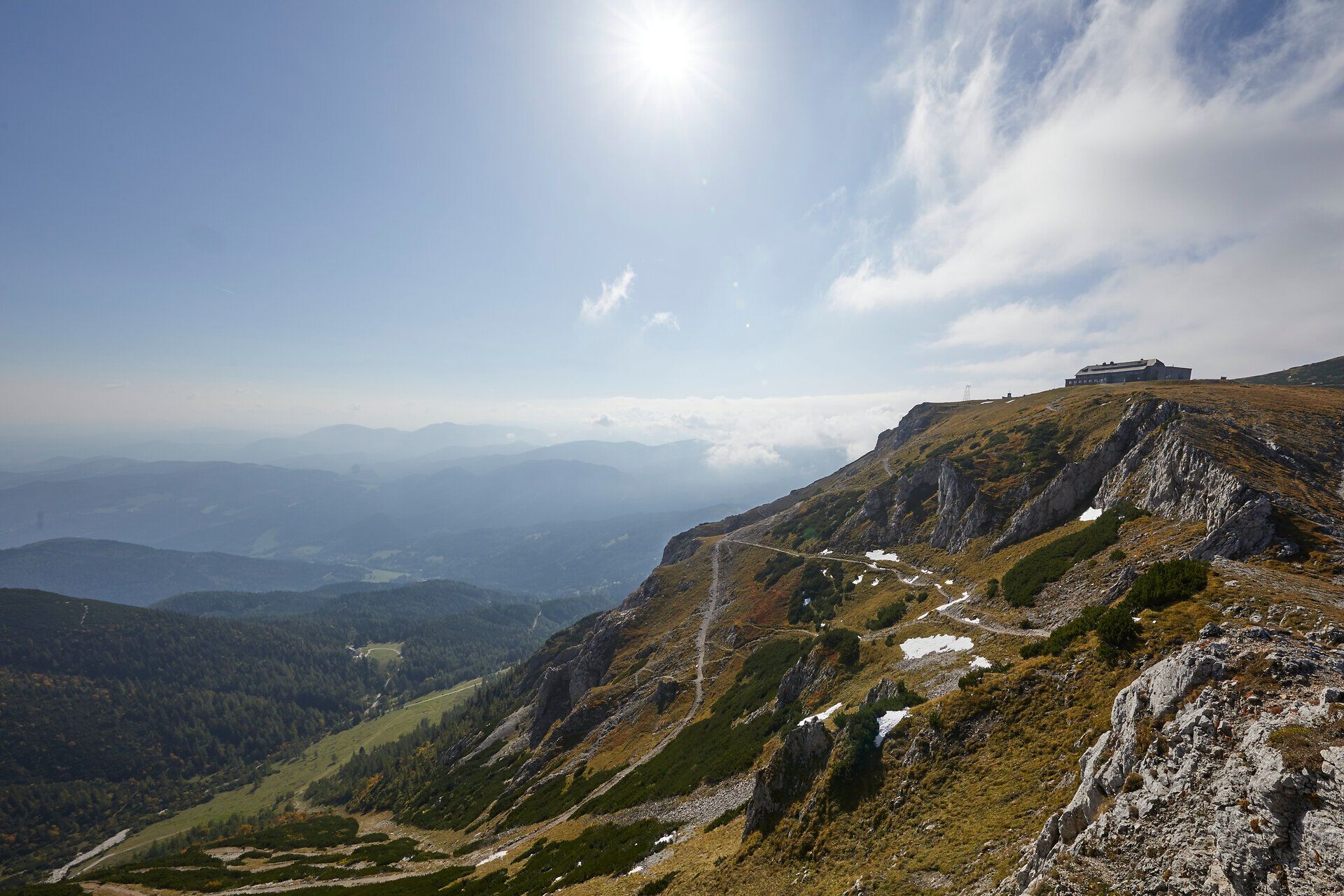 Weitblick über alpine Berglandschaft mit Wanderweg und Felsflanken.