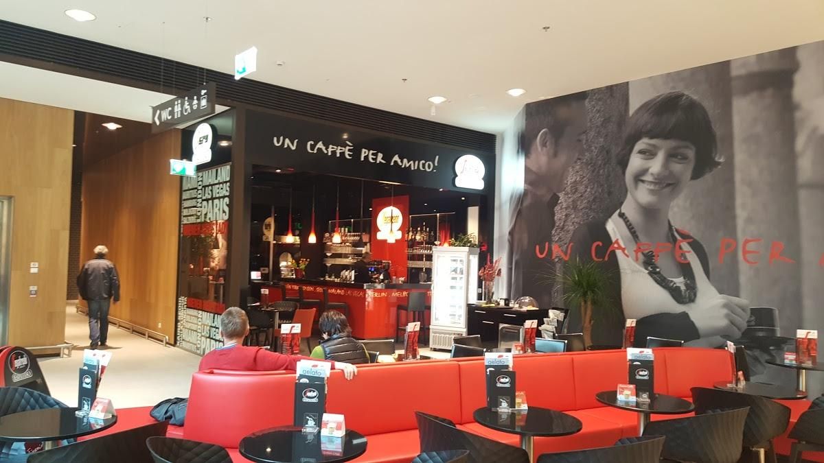 Innenansicht eines Cafés mit roten Sitzbänken und einem großen Wandbild einer lächelnden Frau.