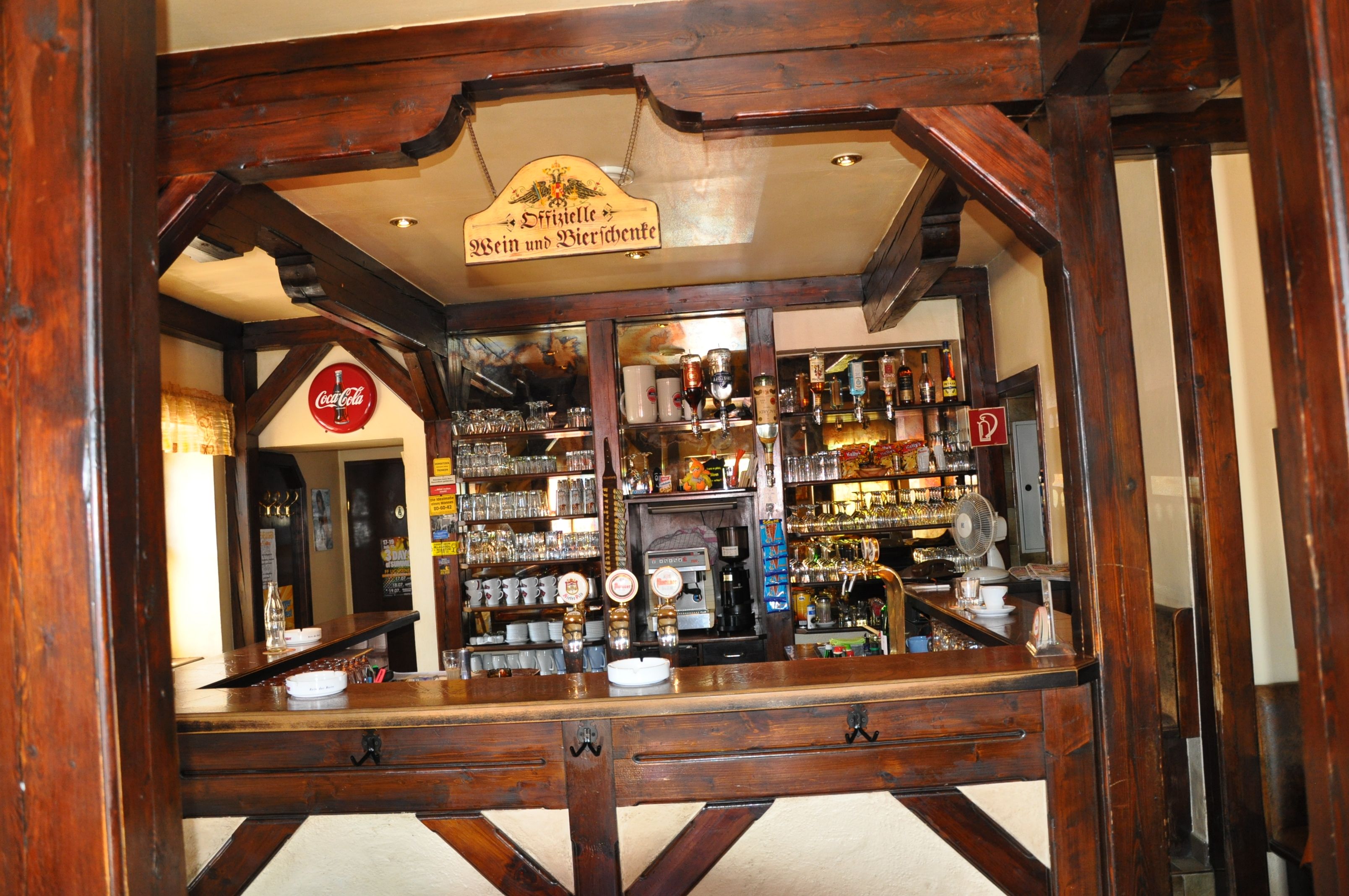 Innenansicht einer rustikalen Bar mit Holzbalken und einer gut bestückten Theke.