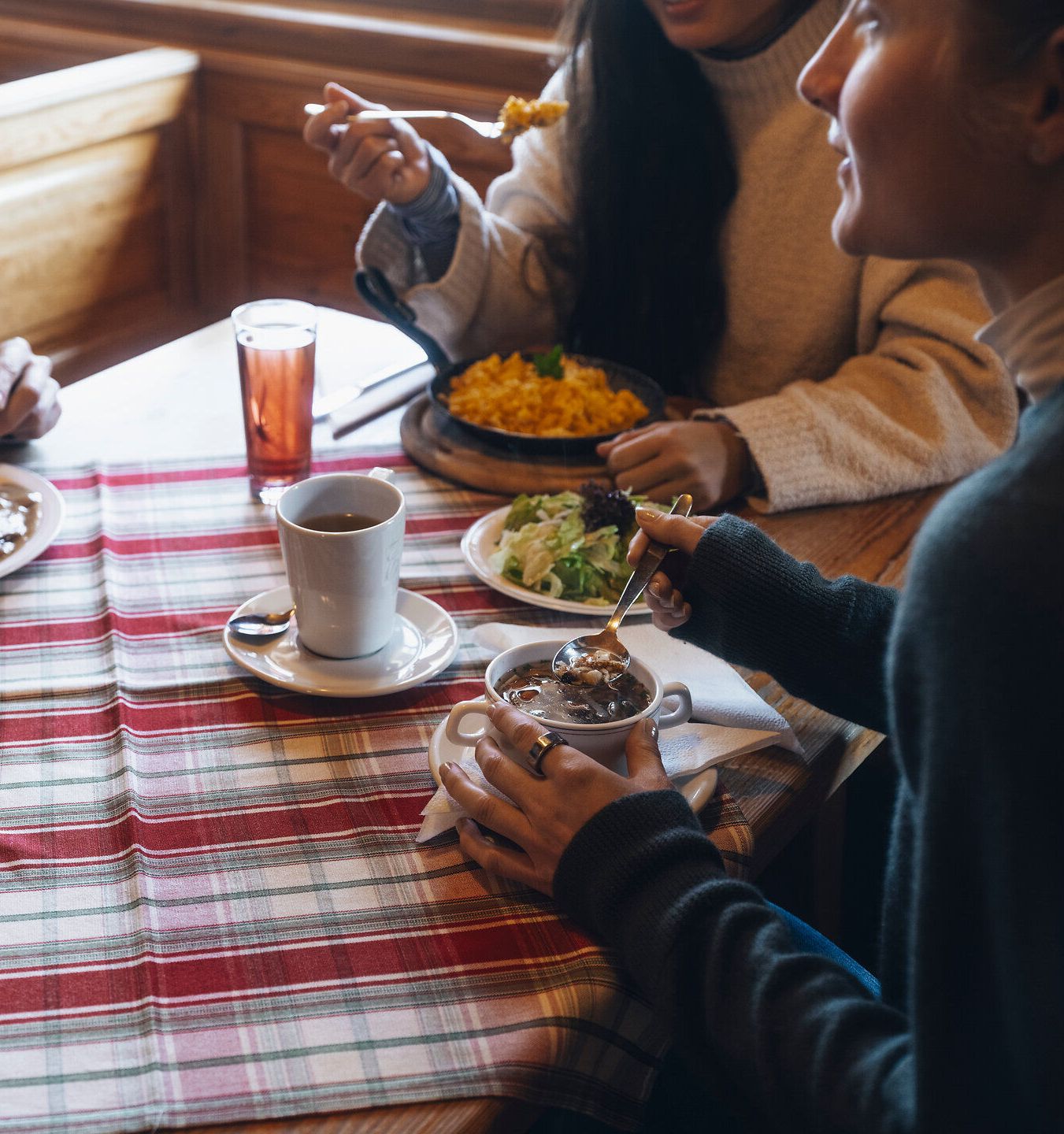 Inmitten der winterlichen Landschaft genießen Freunde ein herzhaftes Mahl, während dampfender Kaffee und frische Salate den Tisch zieren. Die gemütliche Atmosphäre und das knisternde Holzfeuer laden dazu ein, die Seele baumeln zu lassen und die winterliche Idylle der Wiener Alpen zu erleben.