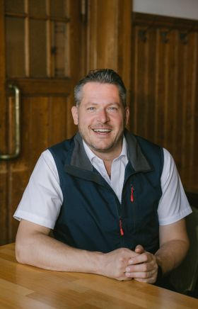 Lächelnder Mitarbeiter am Tisch im Raxalm-Berggasthof
