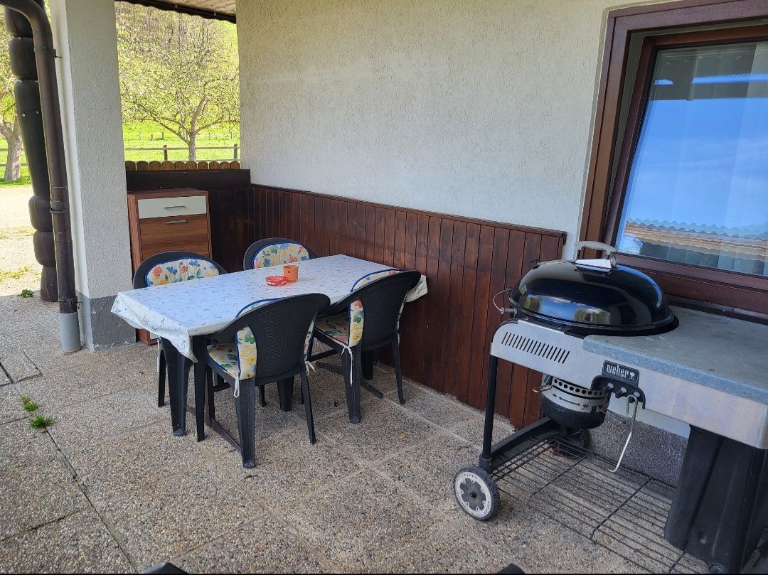 Terrasse mit Tisch, Stühlen und Grill.