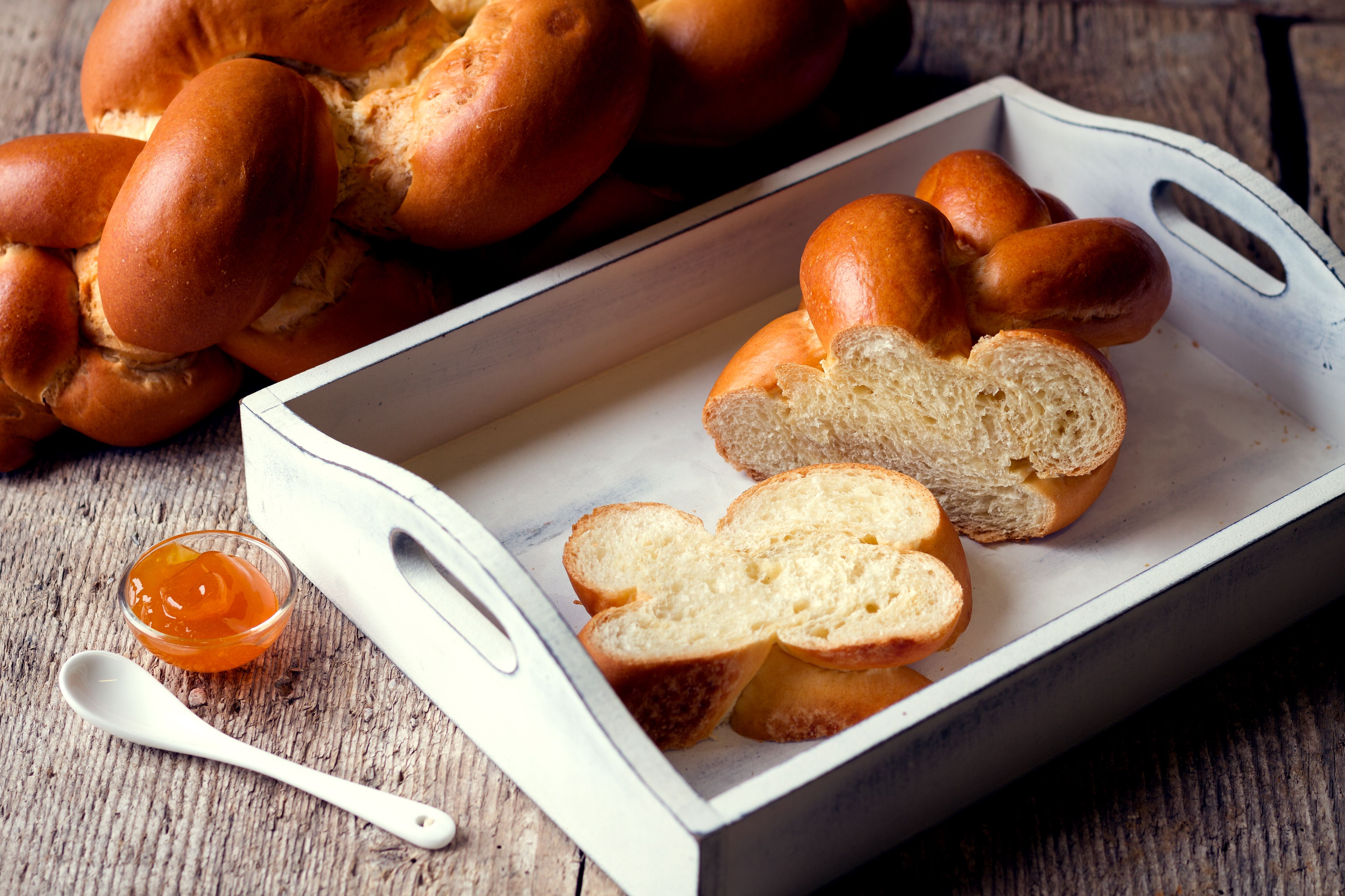 Ein weißes Tablett mit Striezel, daneben eine Schale mit Marmelade.