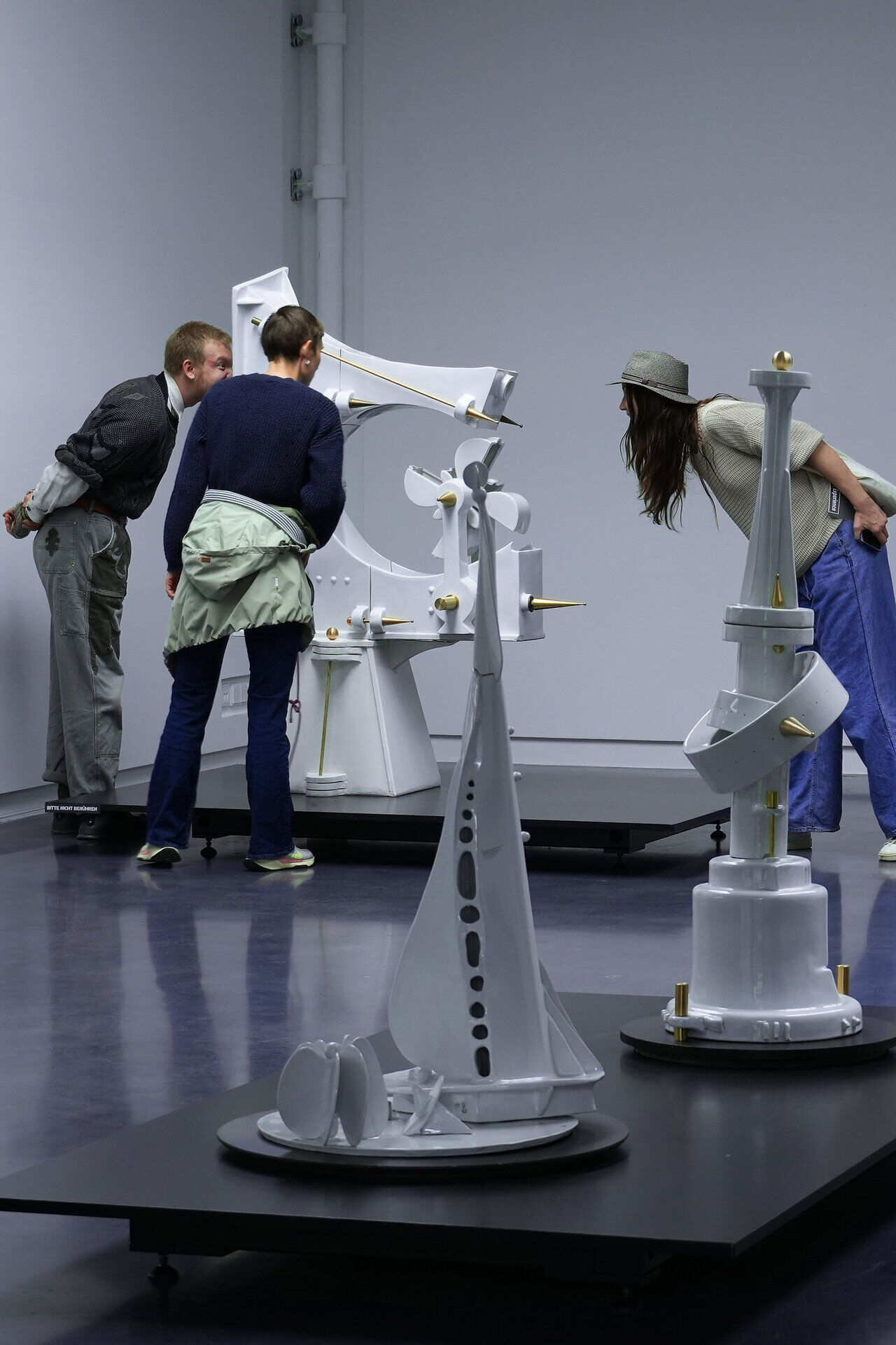 Besucherinnen und Besucher betrachten eine moderne kinetische Kunstinstallation in einem Ausstellungsraum.
