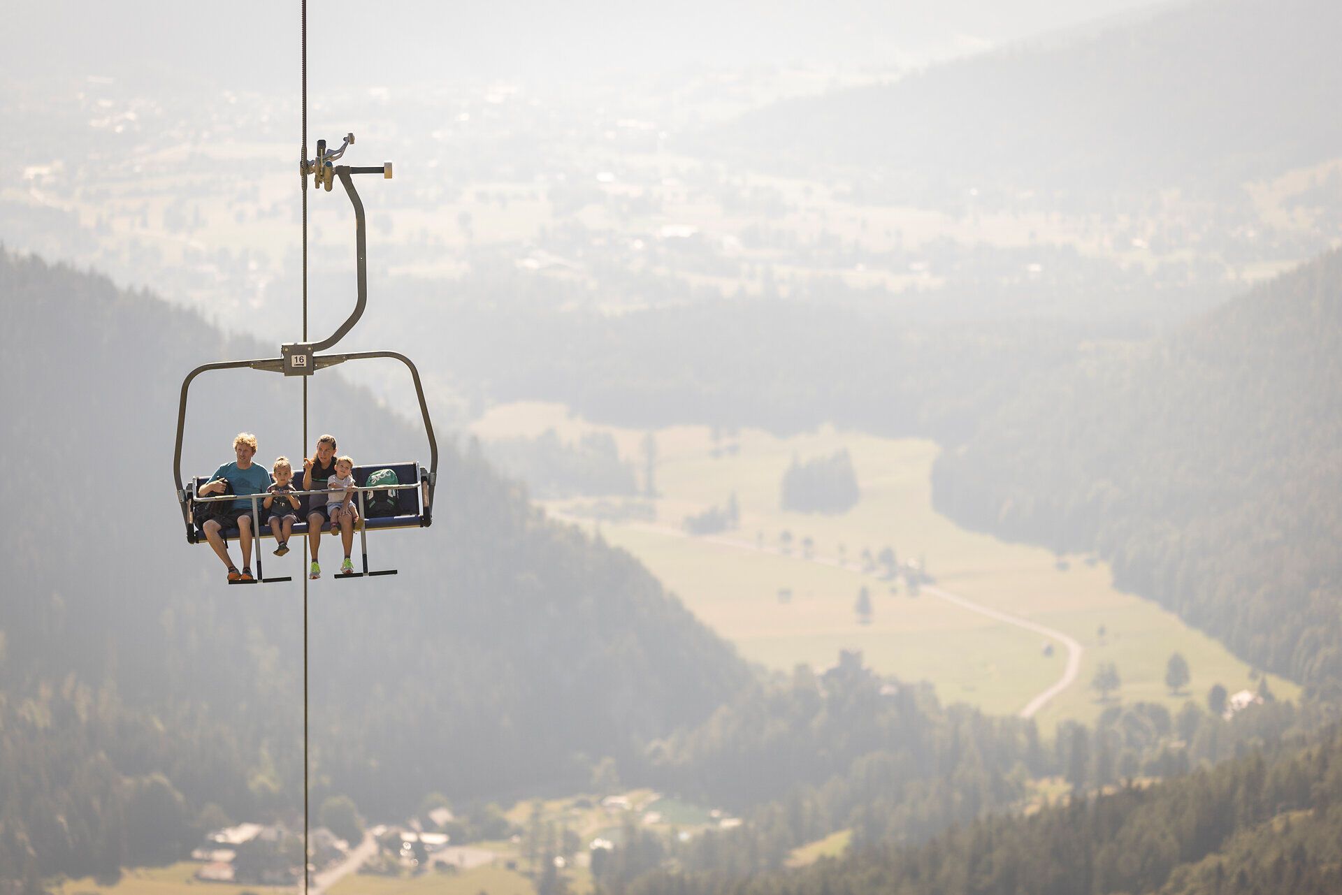 In der sanften Umarmung der Wiener Alpen schwingen sich fröhliche Familienmitglieder in einem Sessellift nach oben. Die atemberaubende Aussicht auf die umliegenden Täler und Berge verspricht ein unvergessliches Wanderabenteuer. Hier, wo die Natur in voller Pracht erblüht, wird jeder Moment zum Erlebnis.