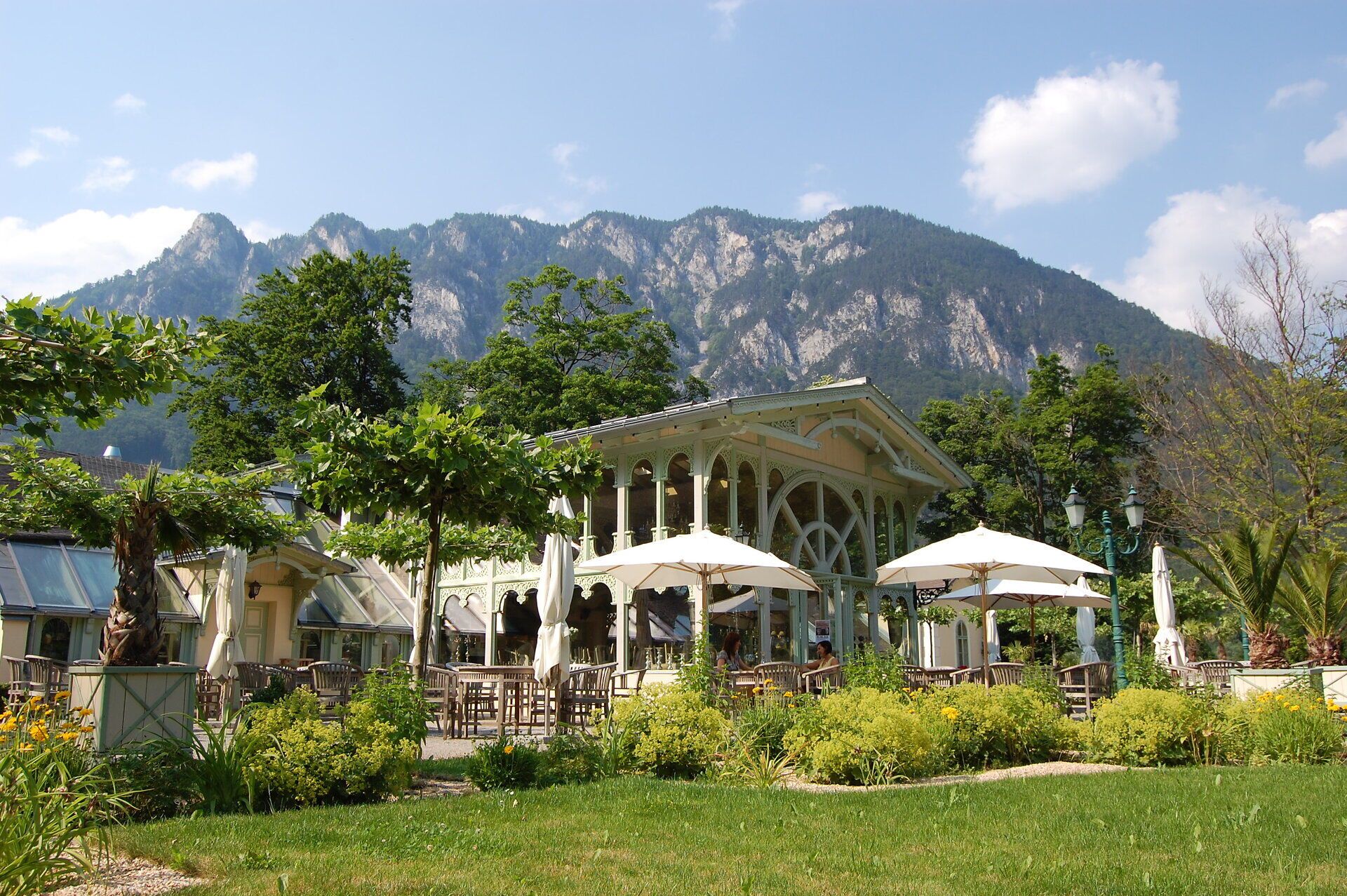 Orangerie Wartholz mit Terrasse und Garten vor der markanten Bergkulisse der Rax unter blauem Himmel.