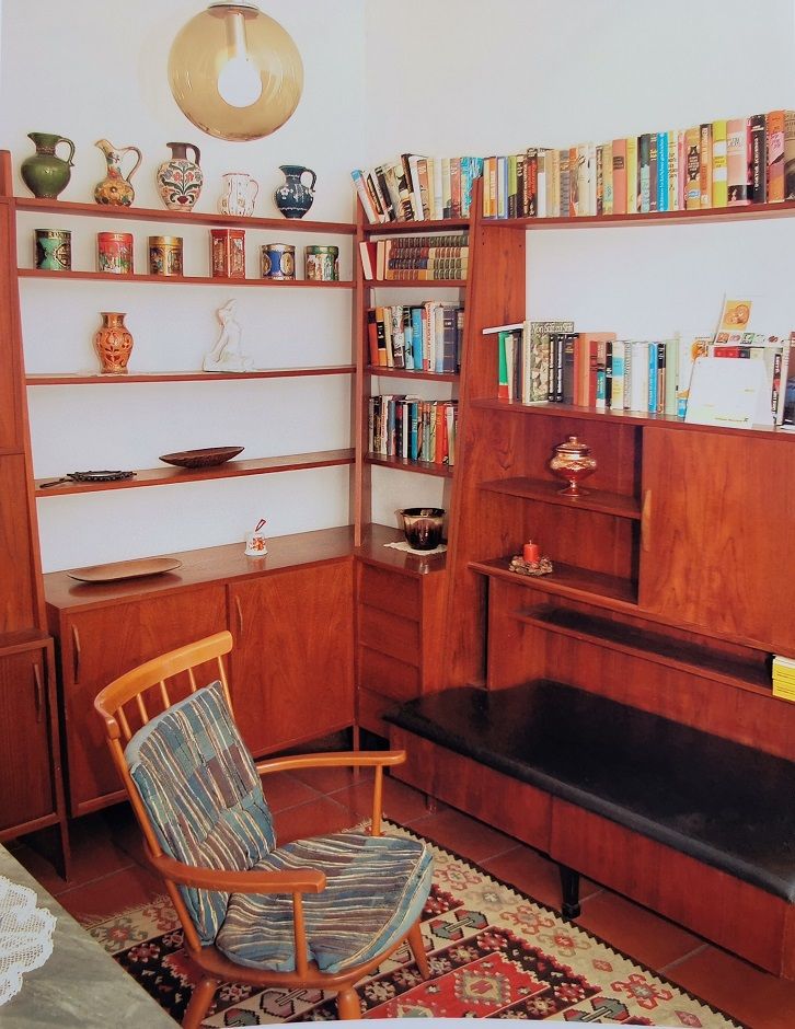 Gemütliche Leseecke mit Holzregalen, Büchern und einem Sessel.