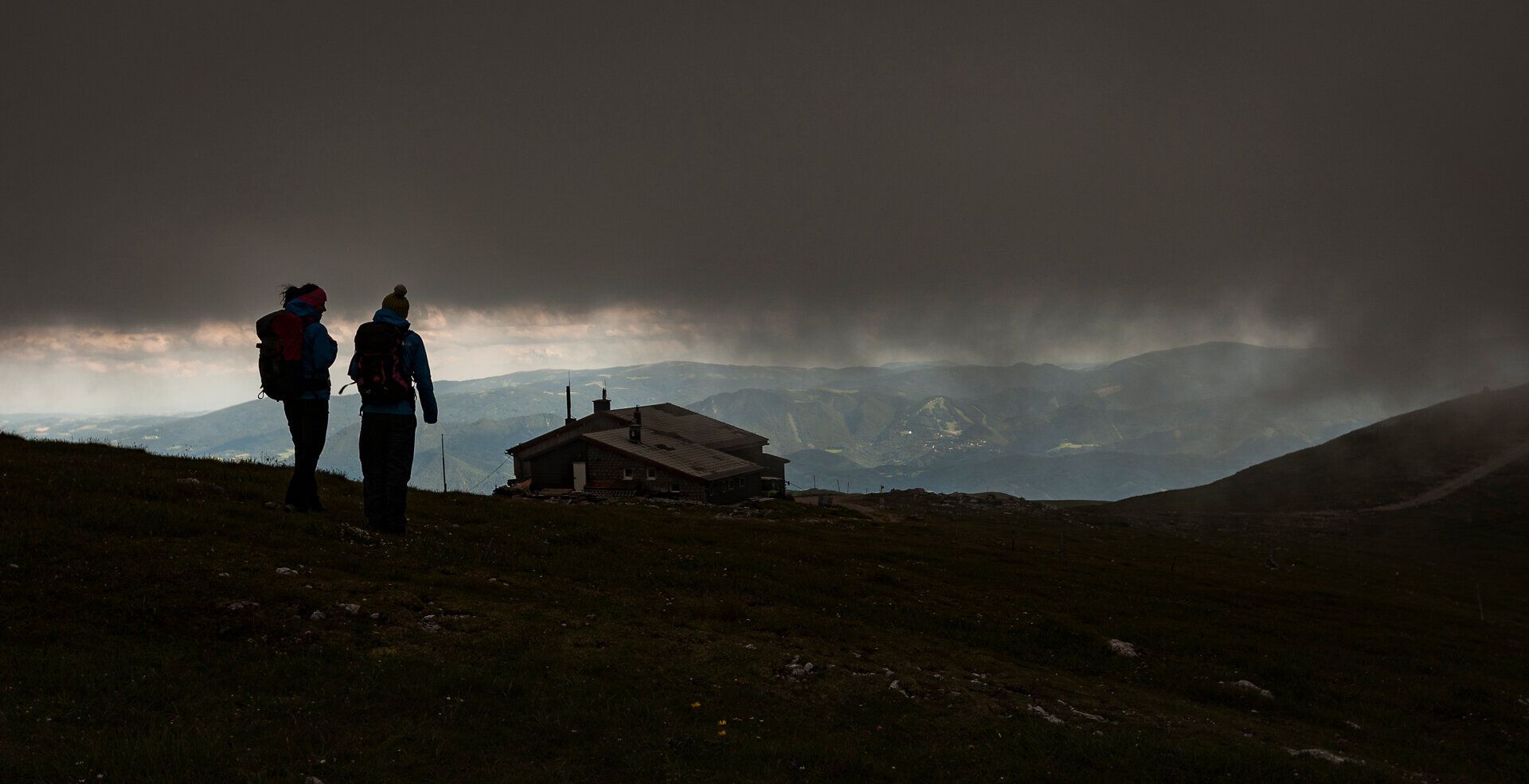 Die Wolken ziehen majestätisch über die Gipfel, während zwei Wanderer in der Ferne stehen und die atemberaubende Aussicht genießen. Die kühle Bergluft und die unberührte Natur schaffen eine friedliche Atmosphäre, die zum Verweilen einlädt. Hier, in den Wiener Alpen, wird der Sommer zu einem unvergesslichen Erlebnis.
