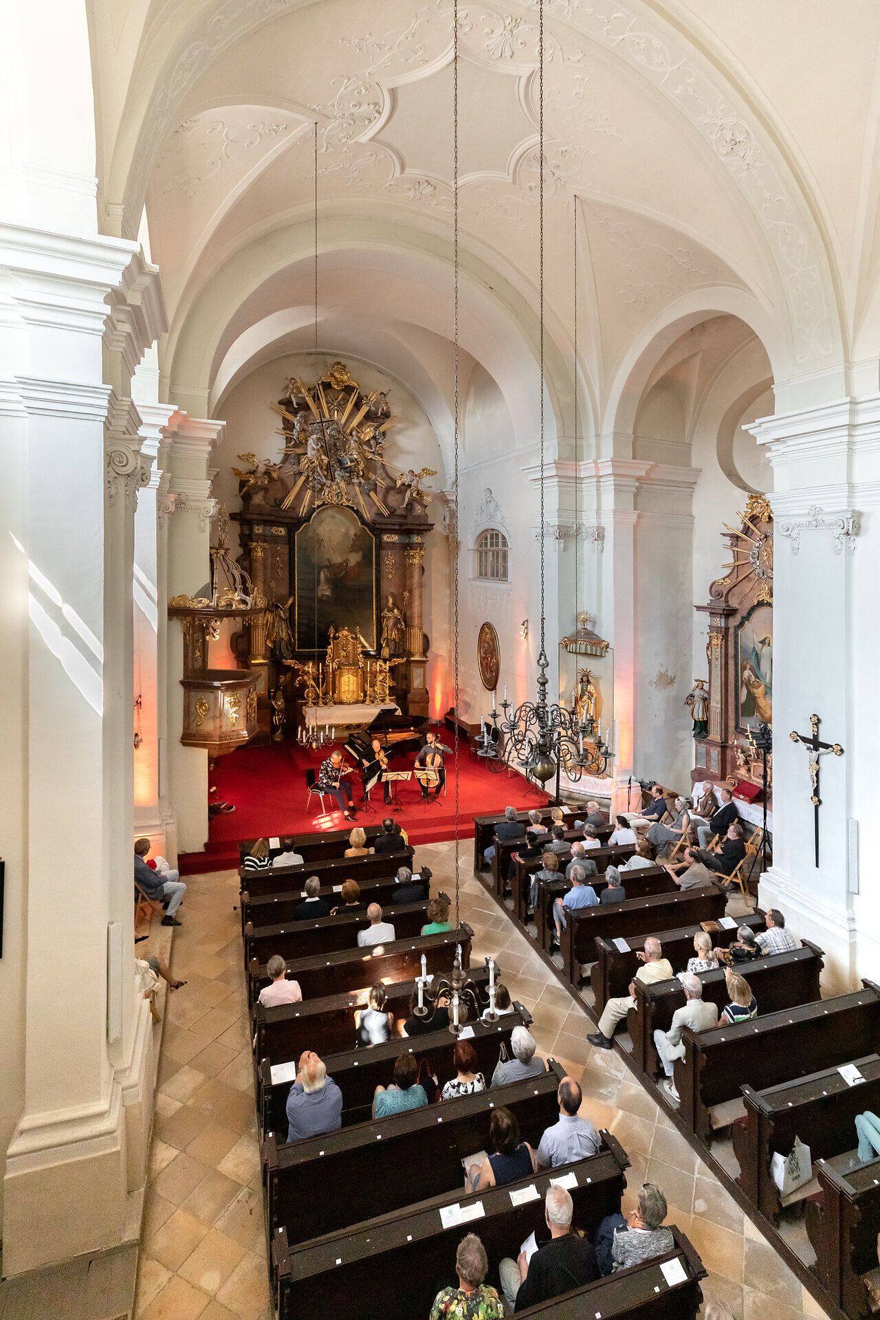 Drei Musiker spielen ein Konzert vor einem Publikum in einer Kirche.