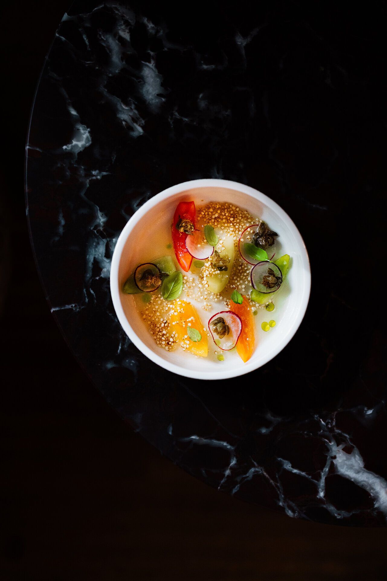 Ein kunstvoll angerichteter Teller präsentiert eine harmonische Komposition aus frischen Tomaten, die in verschiedenen Texturen und Aromen erstrahlen. Die leuchtenden Farben und die feinen Details laden dazu ein, die kulinarische Vielfalt der Region zu entdecken und sich von den Aromen verführen zu lassen.
