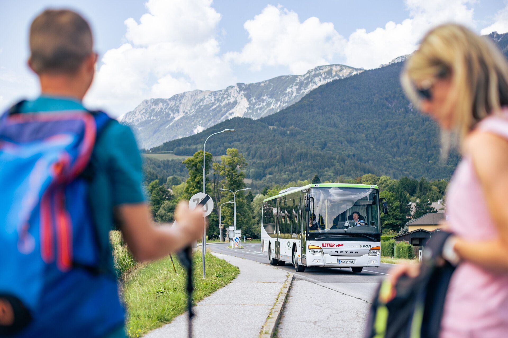 Die frische Bergluft und die atemberaubende Kulisse der majestätischen Alpen laden zu einem unvergesslichen Abenteuer ein. Wanderer mit Rucksäcken und Wanderstöcken warten gespannt auf den nächsten Bus, der sie zu neuen Erlebnissen in die Natur bringt. Hier, wo die Schönheit der Landschaft und die Freude am Entdecken aufeinandertreffen, beginnt der perfekte Sommertag.