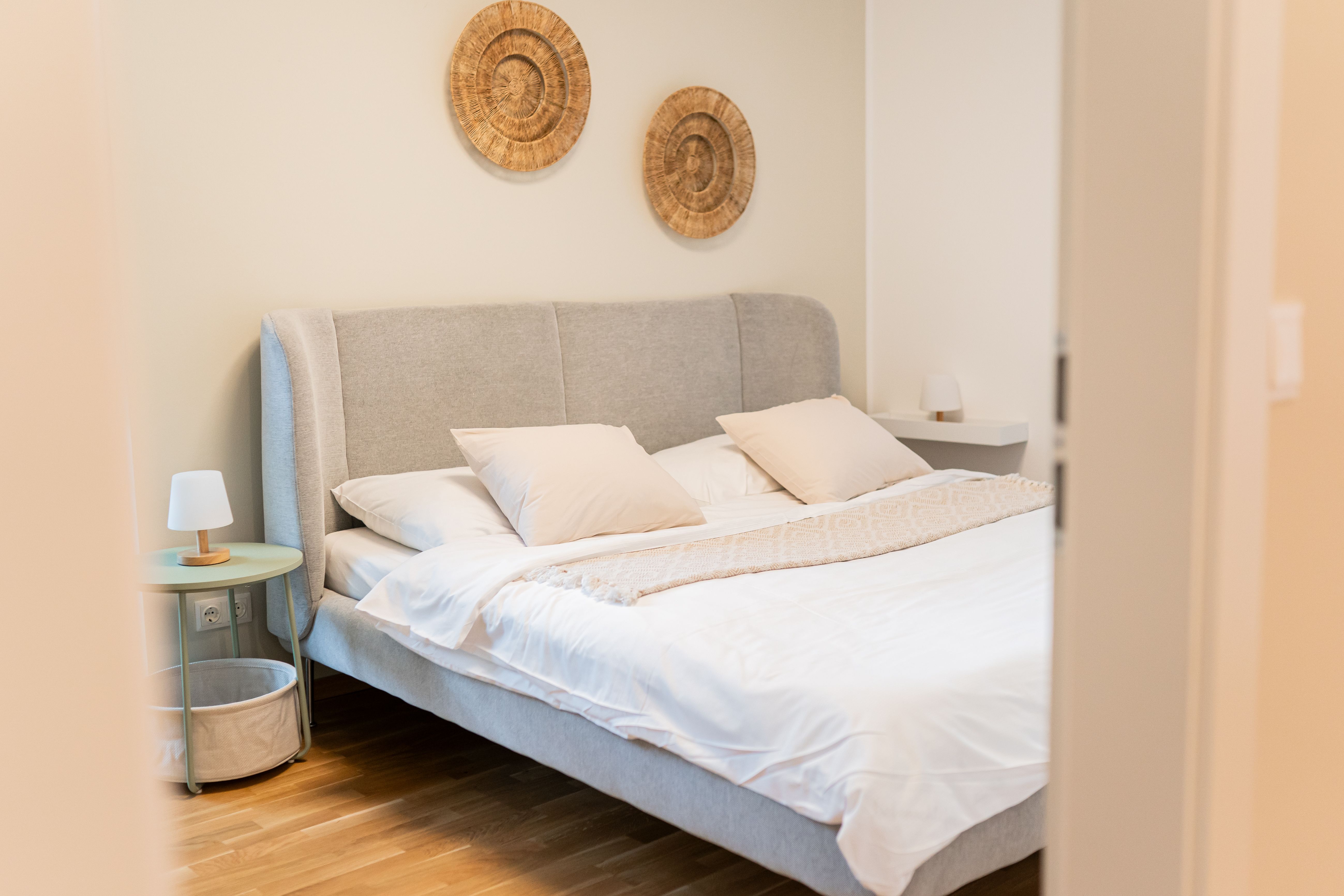 Schlafzimmer mit Doppelbett, Nachttisch und Boho-Dekoration an den Wänden