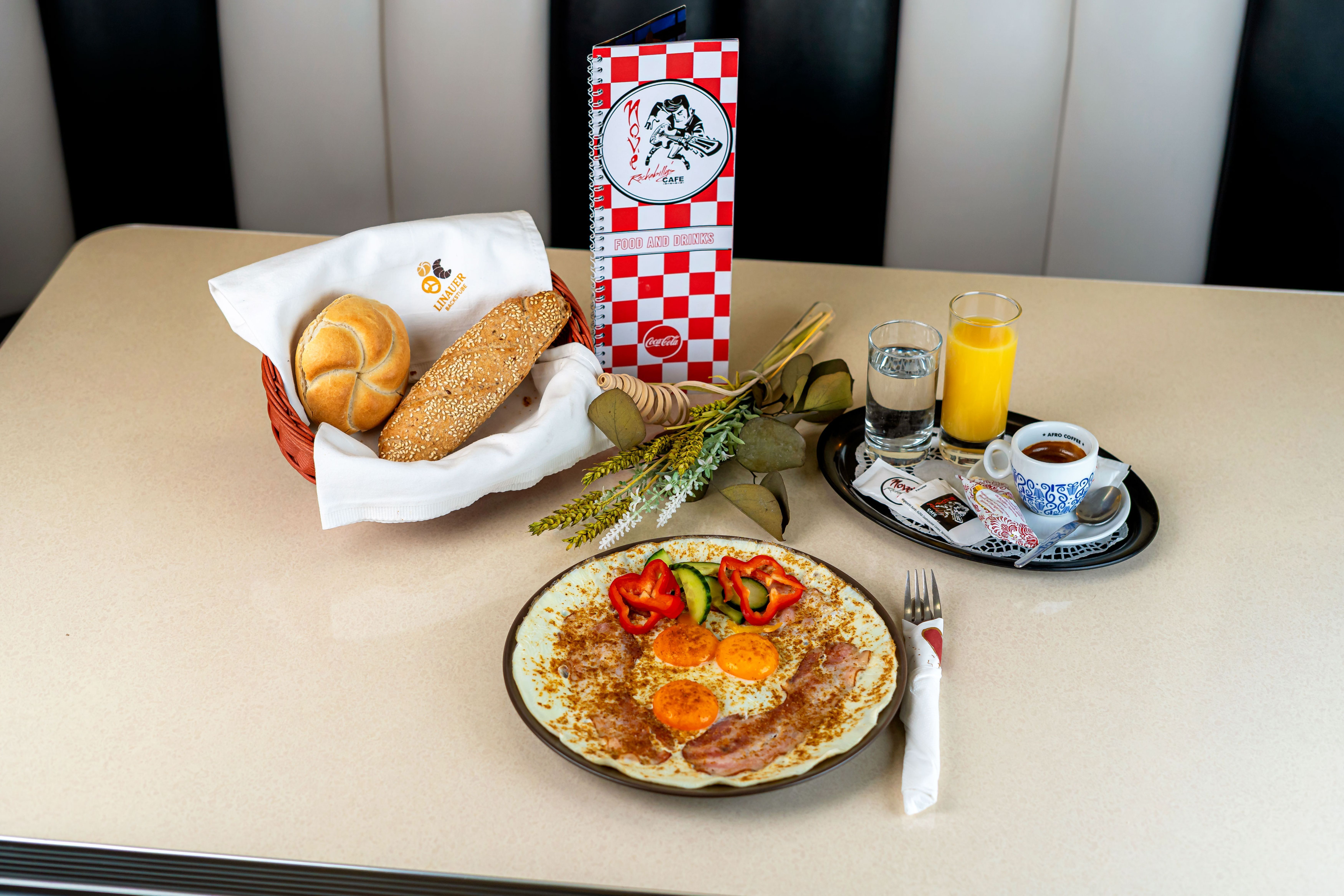 Frühstückstisch mit Omelett, Brötchen, Kaffee, Orangensaft und Wasser im Nové Rockabilly's Cafe.