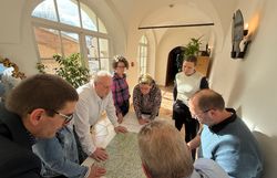 Mehrere Personen stehen über eine Wanderkarte gebeugt an einem Tisch.