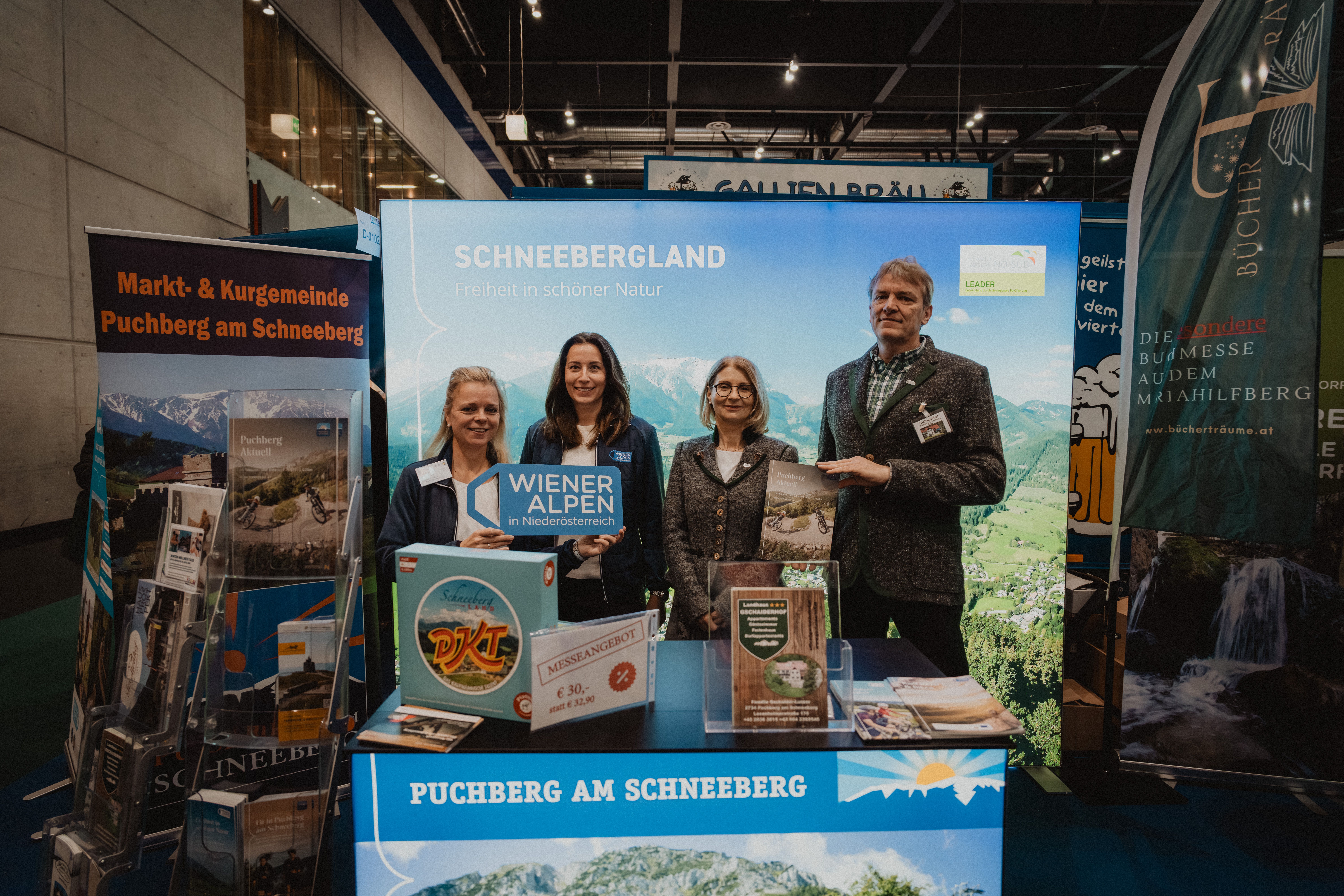 Vier Personen mit dem Schild Wiener Alpen in Niederösterreich vor dem Stand Schneebergland