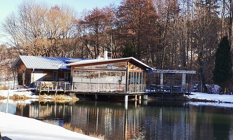 Ein Restaurant am Ufer eines Teiches im Winter, umgeben von Bäumen.