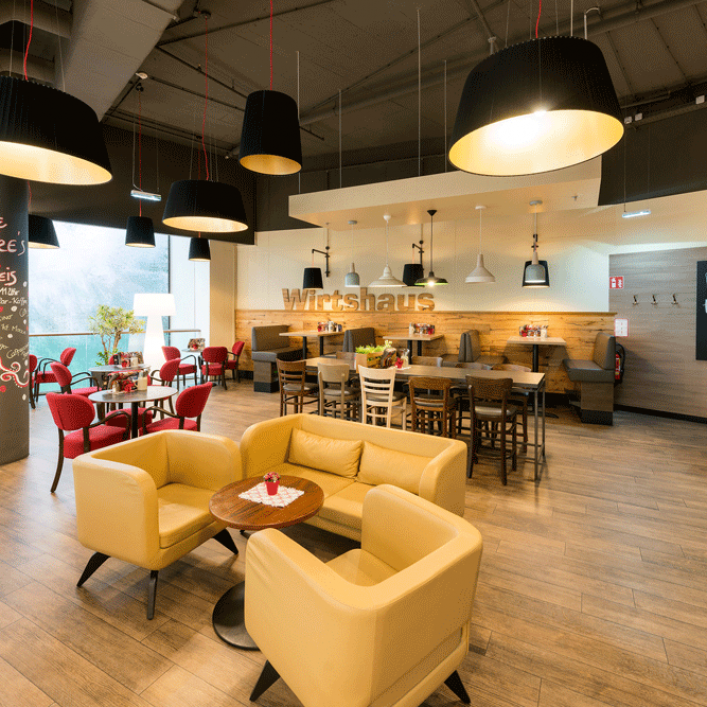Innenansicht eines modernen Wirtshauses mit gelben Sesseln und Holztischen.