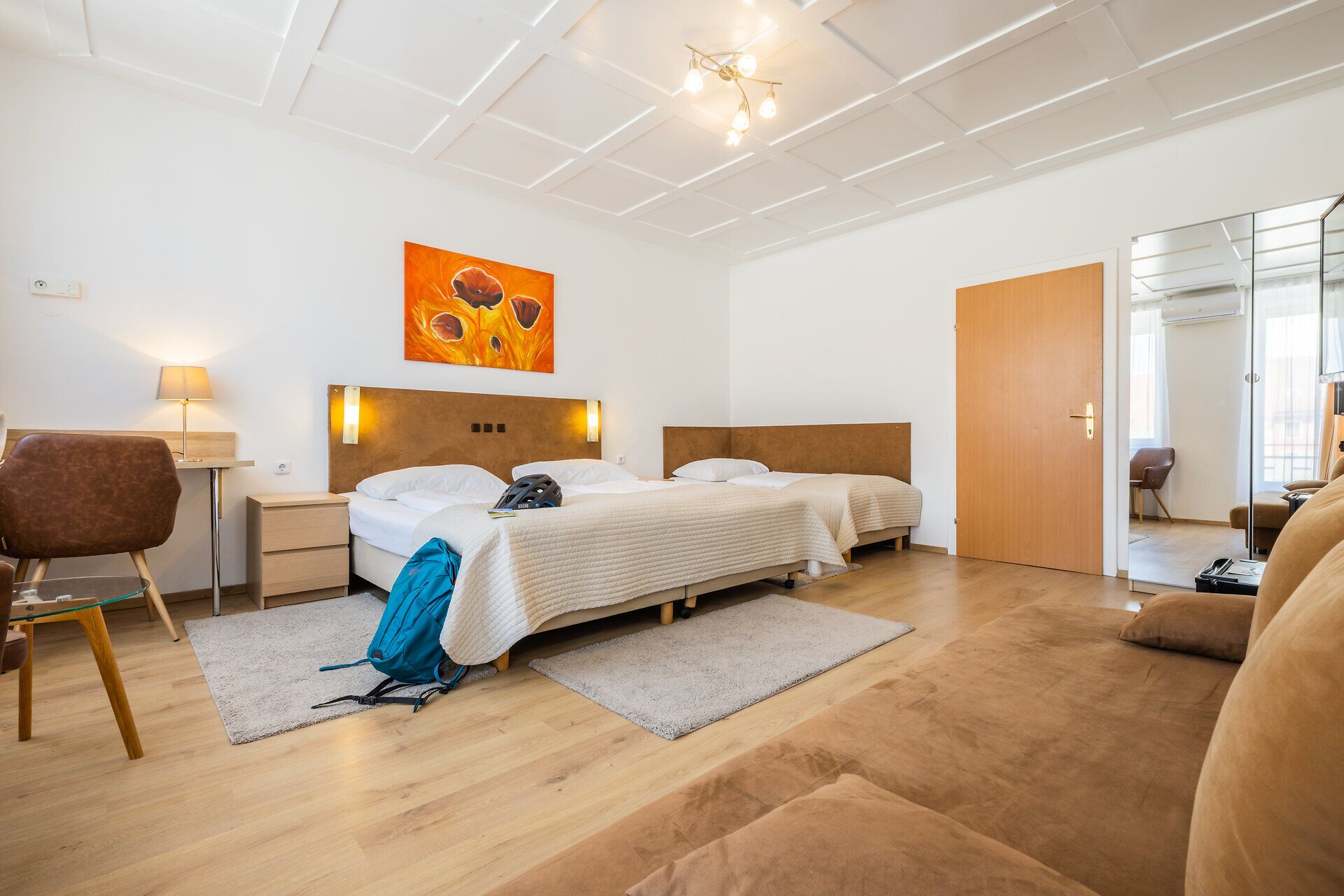 Das Doppelzimmer im traditionsreichen und zentralen Hotel Zentral ist eingerichtet mit einem Doppelbett, einem Einzelbett sowie einer Couch, Schreibtisch und Spiegelschrank.