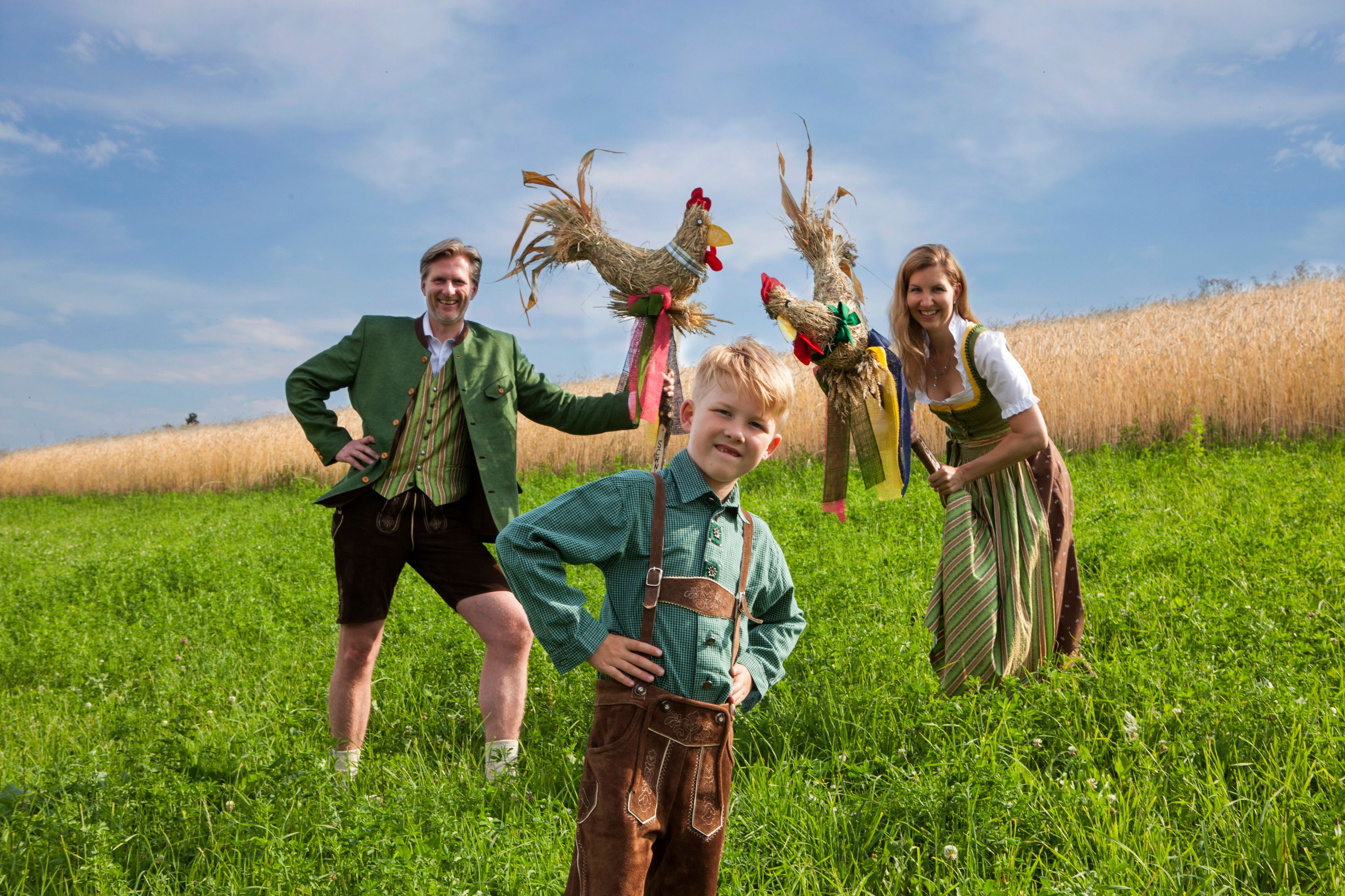 Eine Frau, ein Mann und ein Kind in Tracht gekleidet auf einem Feld.