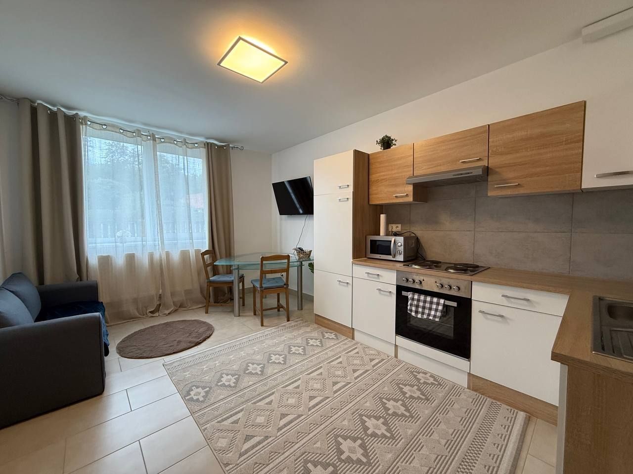 Modern eingerichtetes Apartment mit Küche, Esstisch und Sofa.