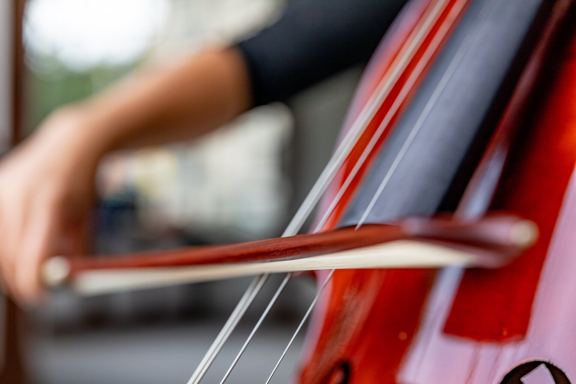 Nahaufnahme einer Person, die mit einem Bogen ein Cello spielt.