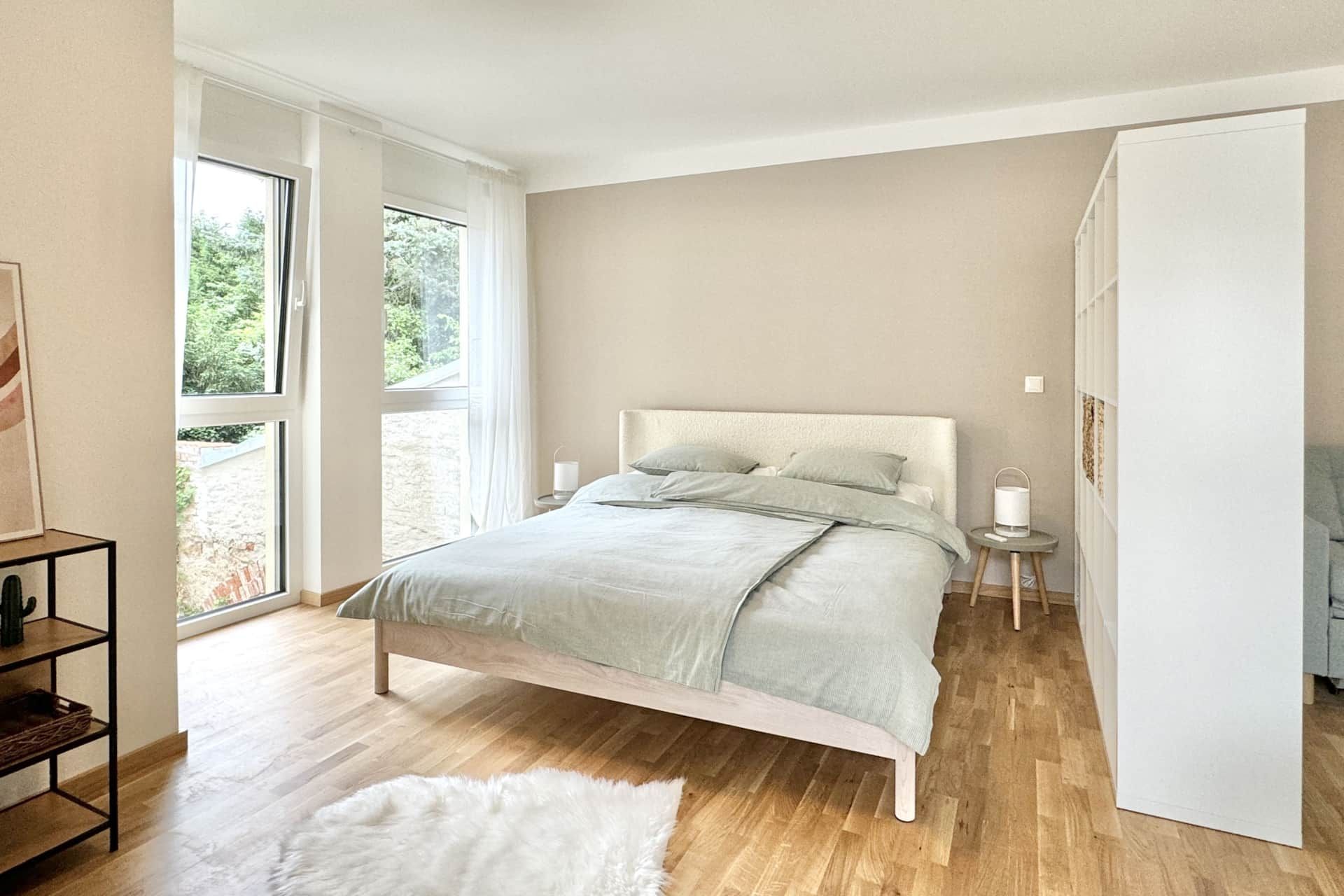 Beiges Schlafzimmer mit großen Fenstern und bequemen Bett