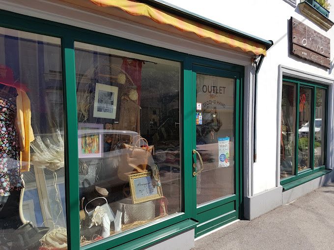 Außenansicht des Second-Hand-Ladens DIVA outlet mit grünen Rahmen und Schaufensterdekoration.