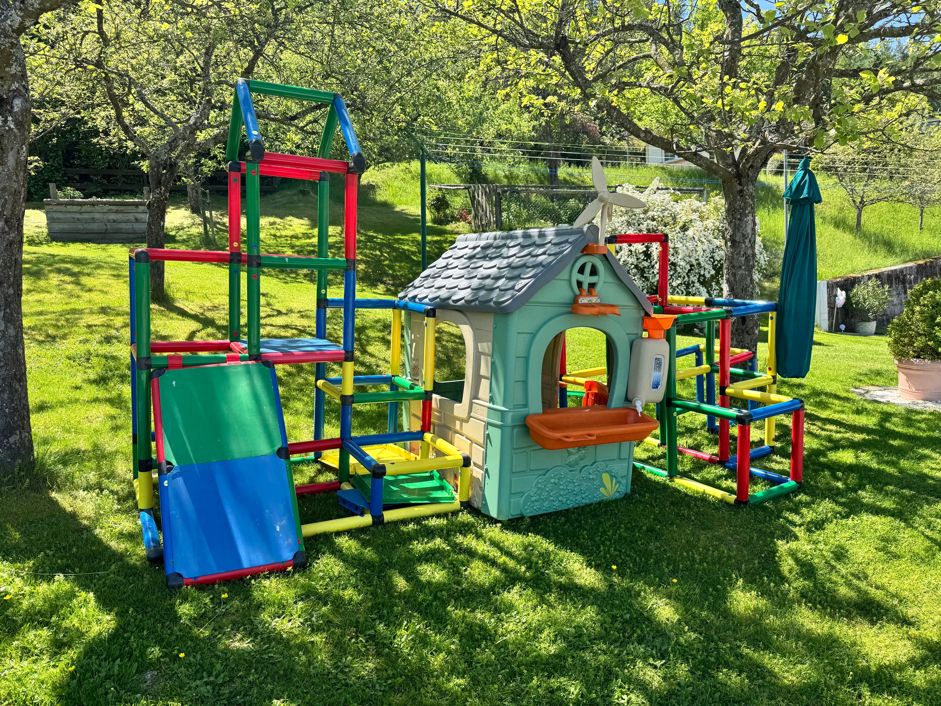 Ein bunter Spielplatz mit Klettergerüst und Spielhaus im Garten.