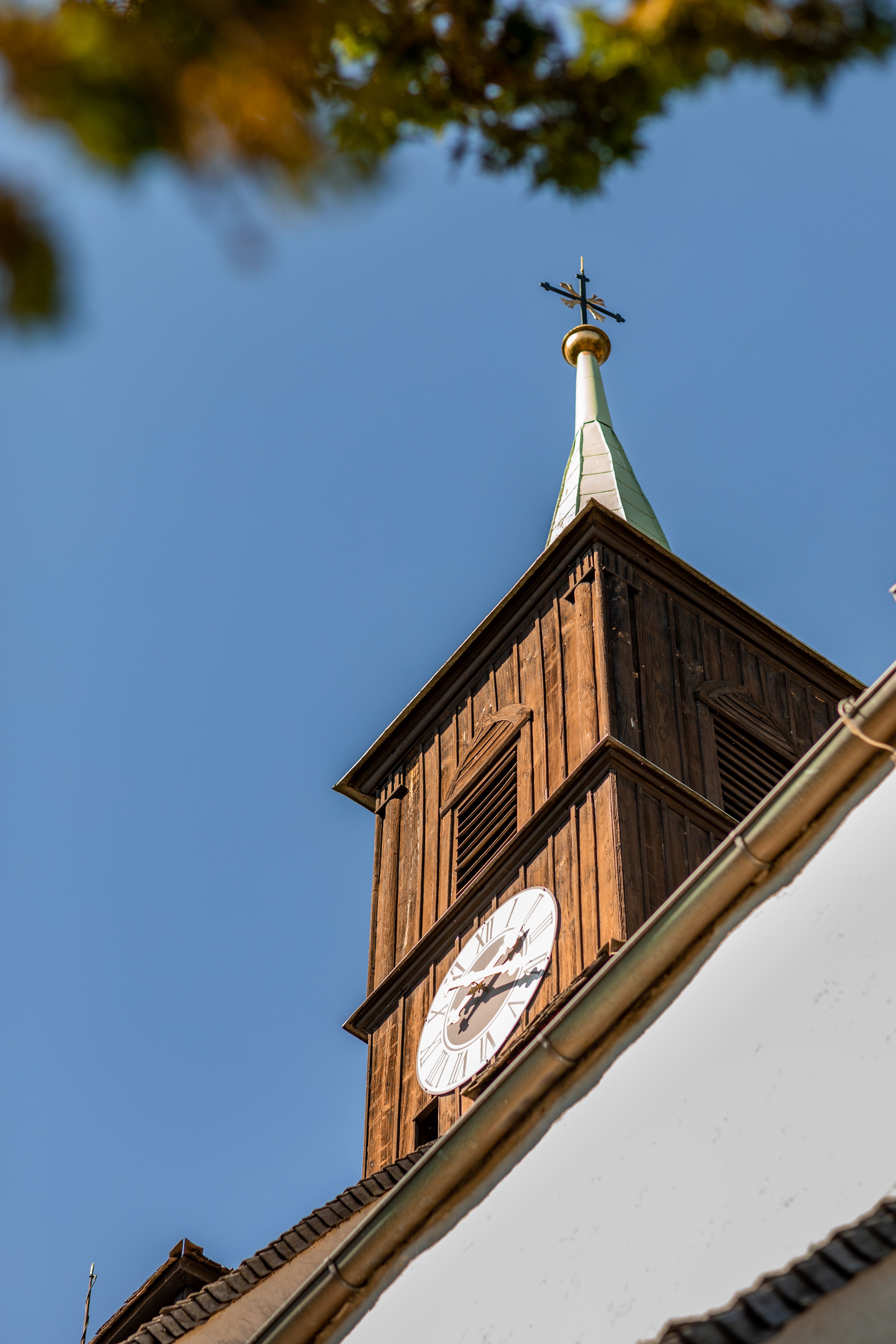 Holzturm der Wehrkirche Bad Schönau mit Uhr und Kreuz an der Spitze