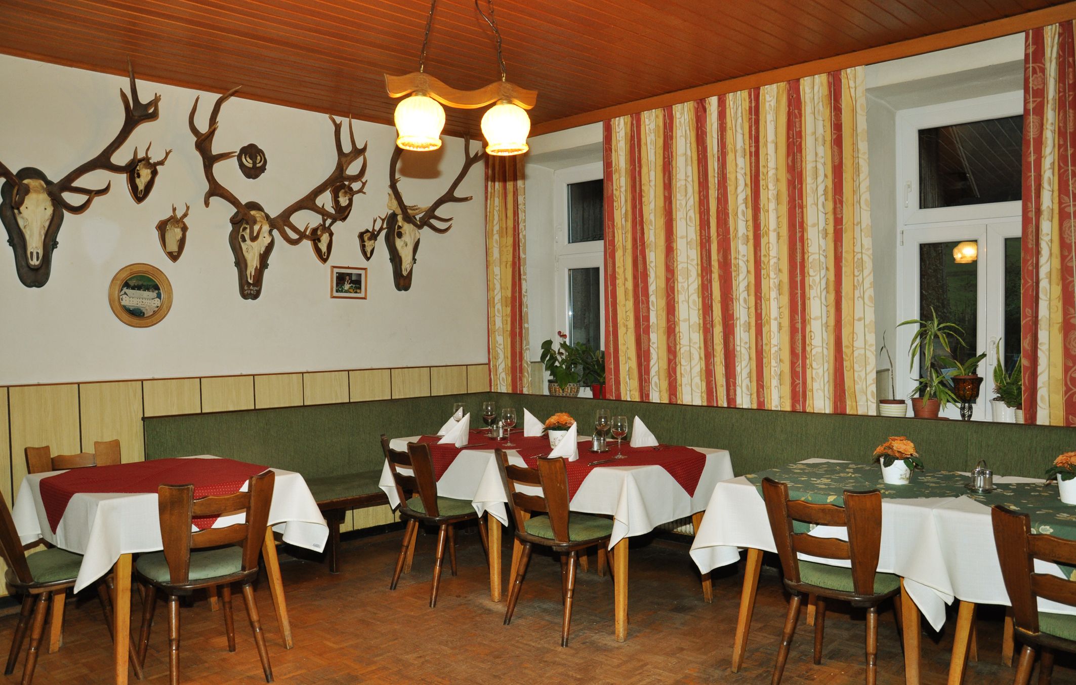 Innenansicht eines traditionellen Gasthofs mit Holzmöbeln und Geweihen an der Wand.