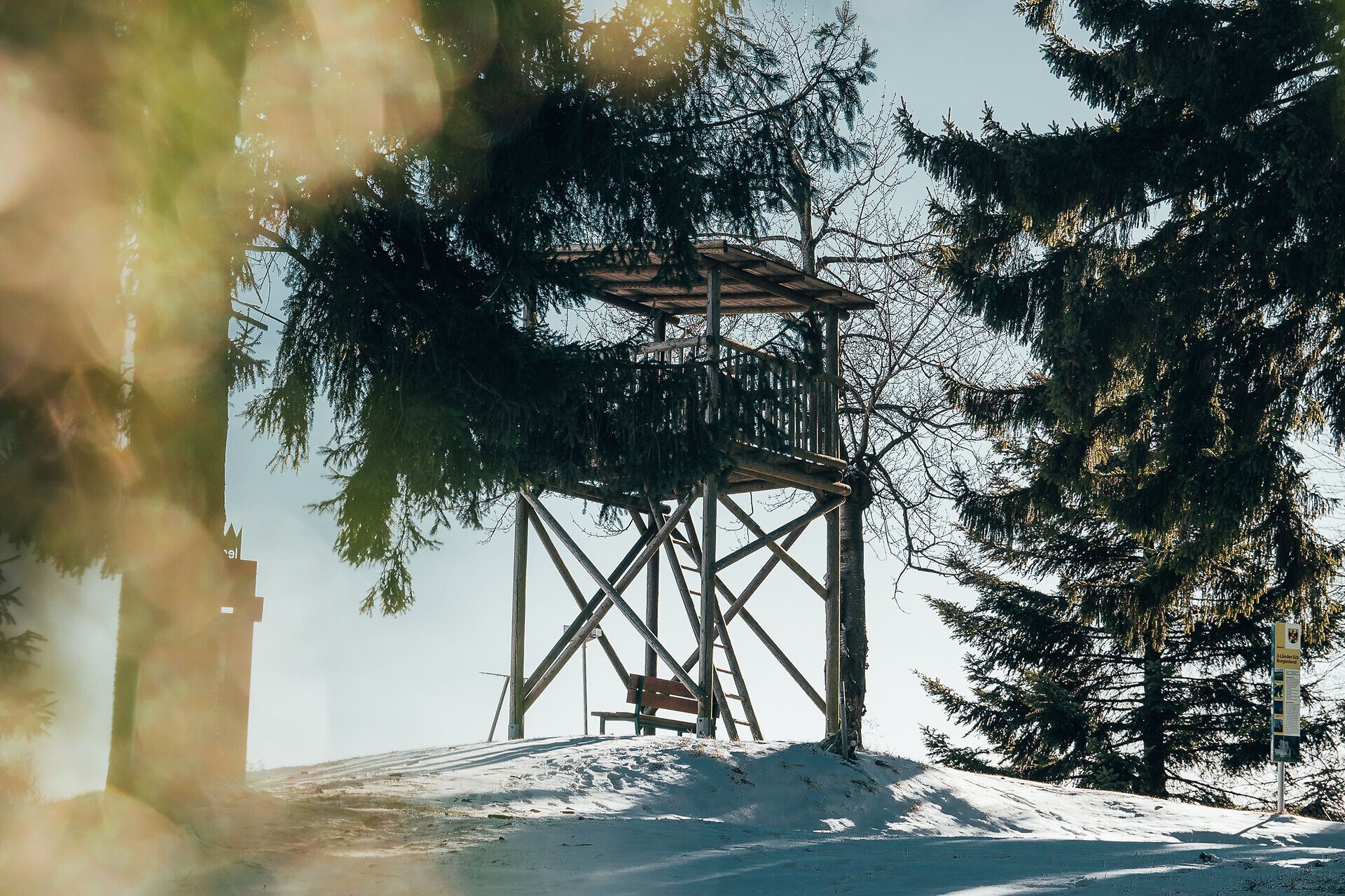 Inmitten einer winterlichen Landschaft erhebt sich eine rustikale Aussichtswarte, umgeben von schneebedeckten Bäumen. Der klare Himmel und die frische, kalte Luft laden dazu ein, die atemberaubende Aussicht auf die verschneiten Hügel der Wiener Alpen zu genießen. Ein perfekter Ort für Naturliebhaber, um die Ruhe und Schönheit der Natur zu erleben.