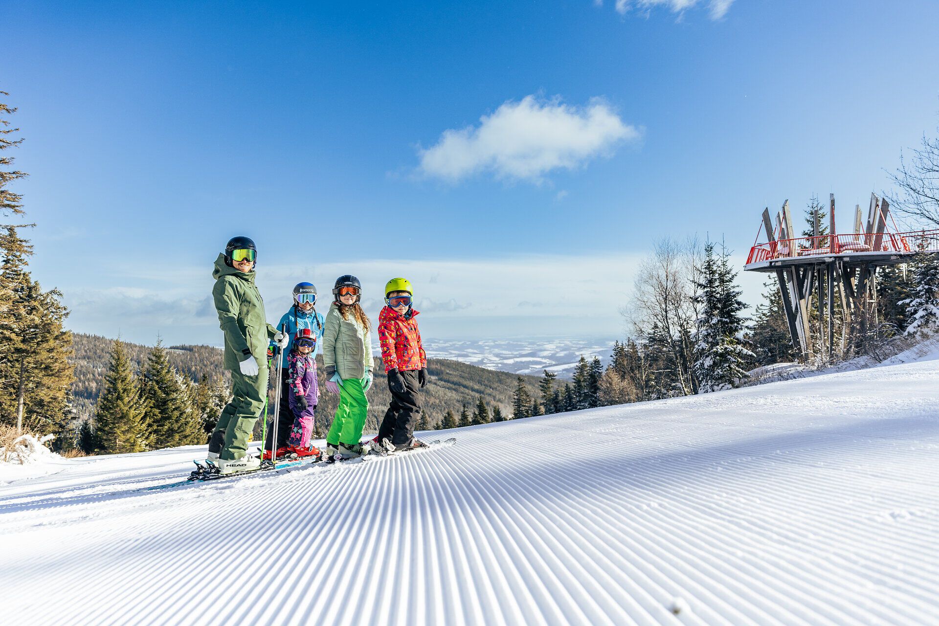 Eine fröhliche Familie genießt den Wintertag auf den schneebedeckten Pisten, umgeben von der atemberaubenden Kulisse der Wiener Alpen. Die strahlende Sonne und der klare Himmel schaffen eine perfekte Atmosphäre für unvergessliche Momente im Schnee. Hier wird das Skifahren zum gemeinsamen Erlebnis für Groß und Klein.