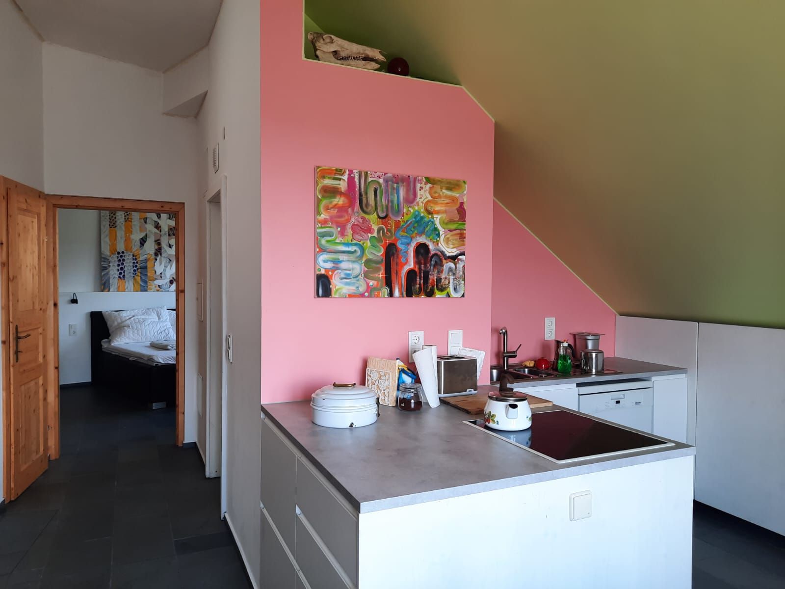 Moderne Küche mit rosa Wand und Kunstwerk, Blick ins Schlafzimmer.