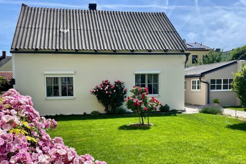 Exterior view of the house with green lawn, flower beds, shrubs and trees