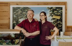 Zwei Personen in roten Hemden stehen lächelnd in einem Raum eines Gasthofes.