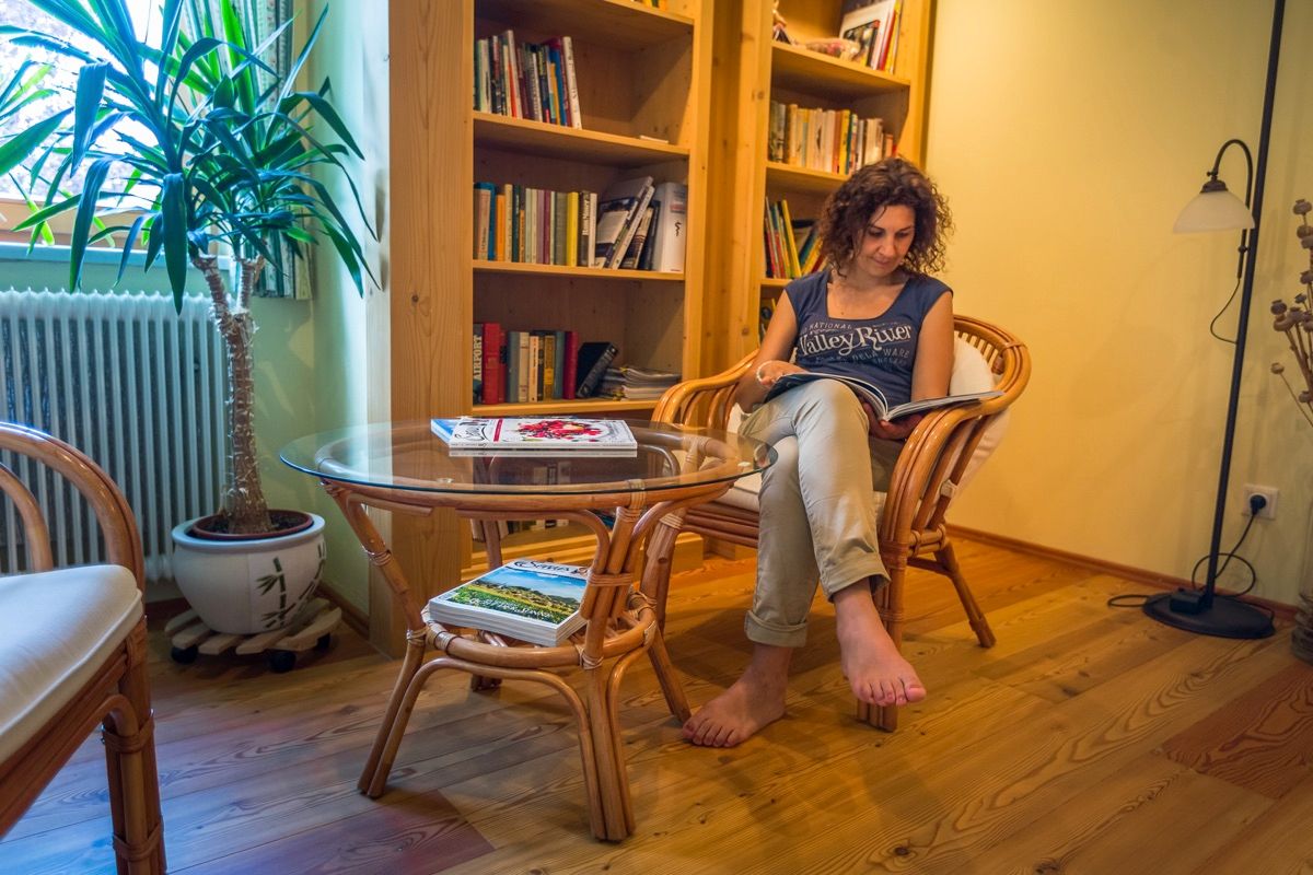 Frau liest in einem gemütlichen Leseraum mit Bücherregal und Pflanzen.