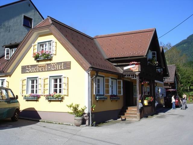 Ein traditionelles Gasthaus mit gelber Fassade und Blumenkästen unter den Fenstern.