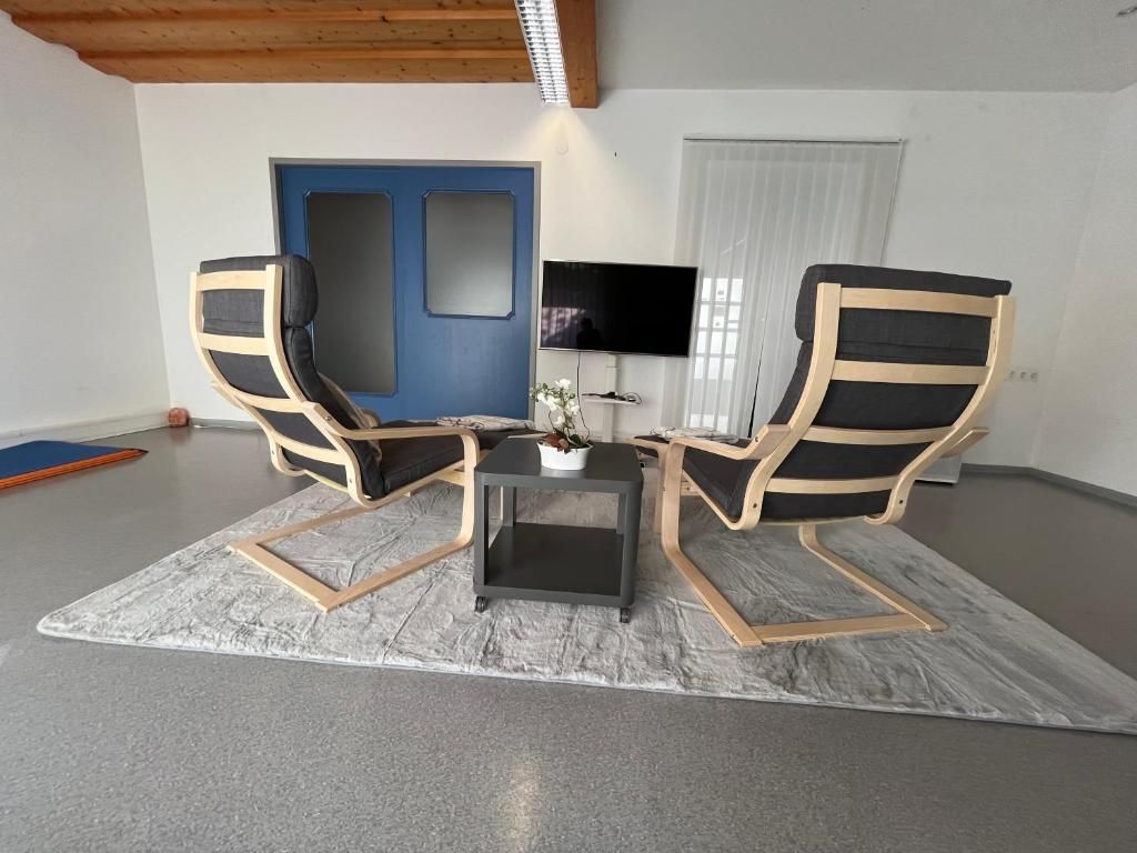 Large room with carpet, TV and 2 comfortable armchairs