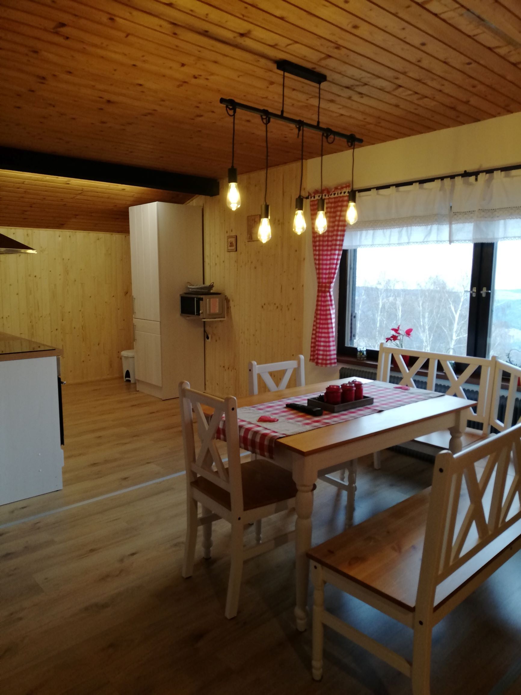 Gemütliches Dachgeschoss-Apartment mit Holzwänden, Esstisch und Hängelampen.