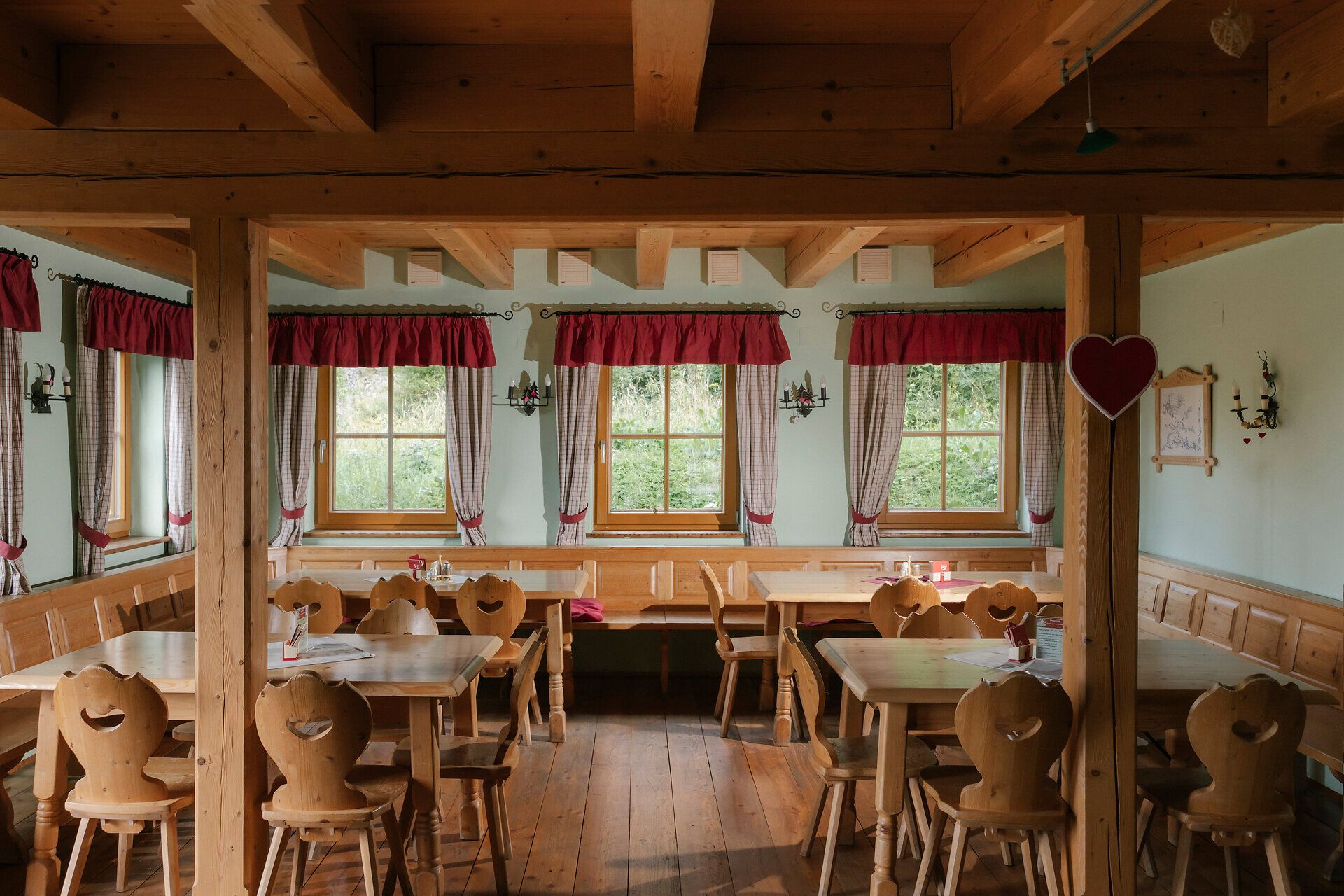 Gastraum mit Holztischen und Vorhängen in der Hengsthütte am Schneeberg