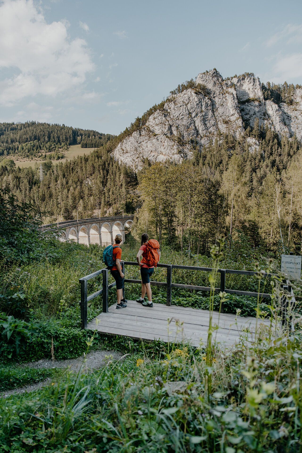 Zwei Wanderer genießen den Ausblick auf die Semmeringbahn