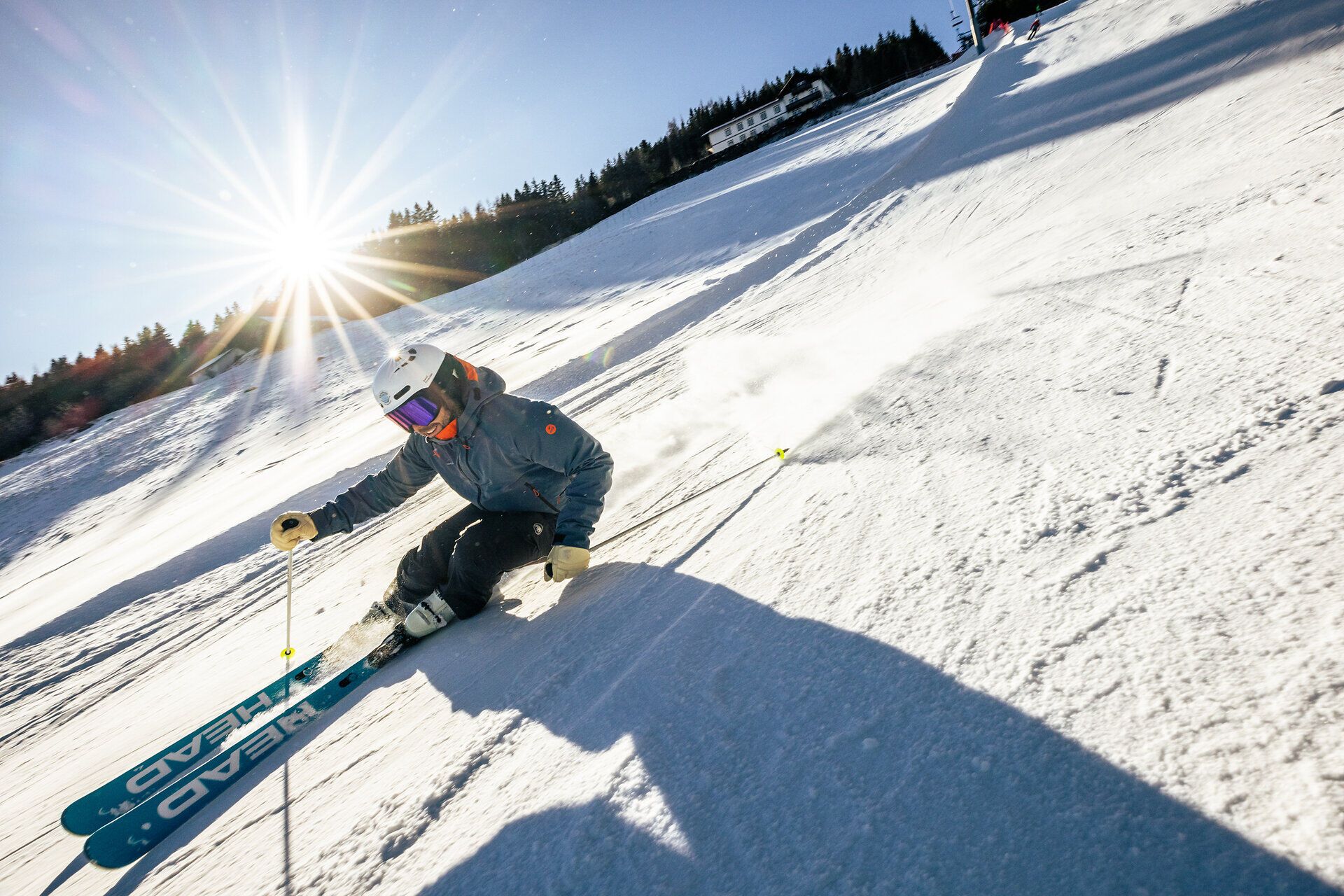 Die strahlende Wintersonne taucht die verschneite Landschaft in ein warmes Licht, während eine Familie fröhlich die Pisten hinunterfährt. Die frische Bergluft und der glitzernde Schnee schaffen eine unvergessliche Atmosphäre für Wintersportler jeden Alters.