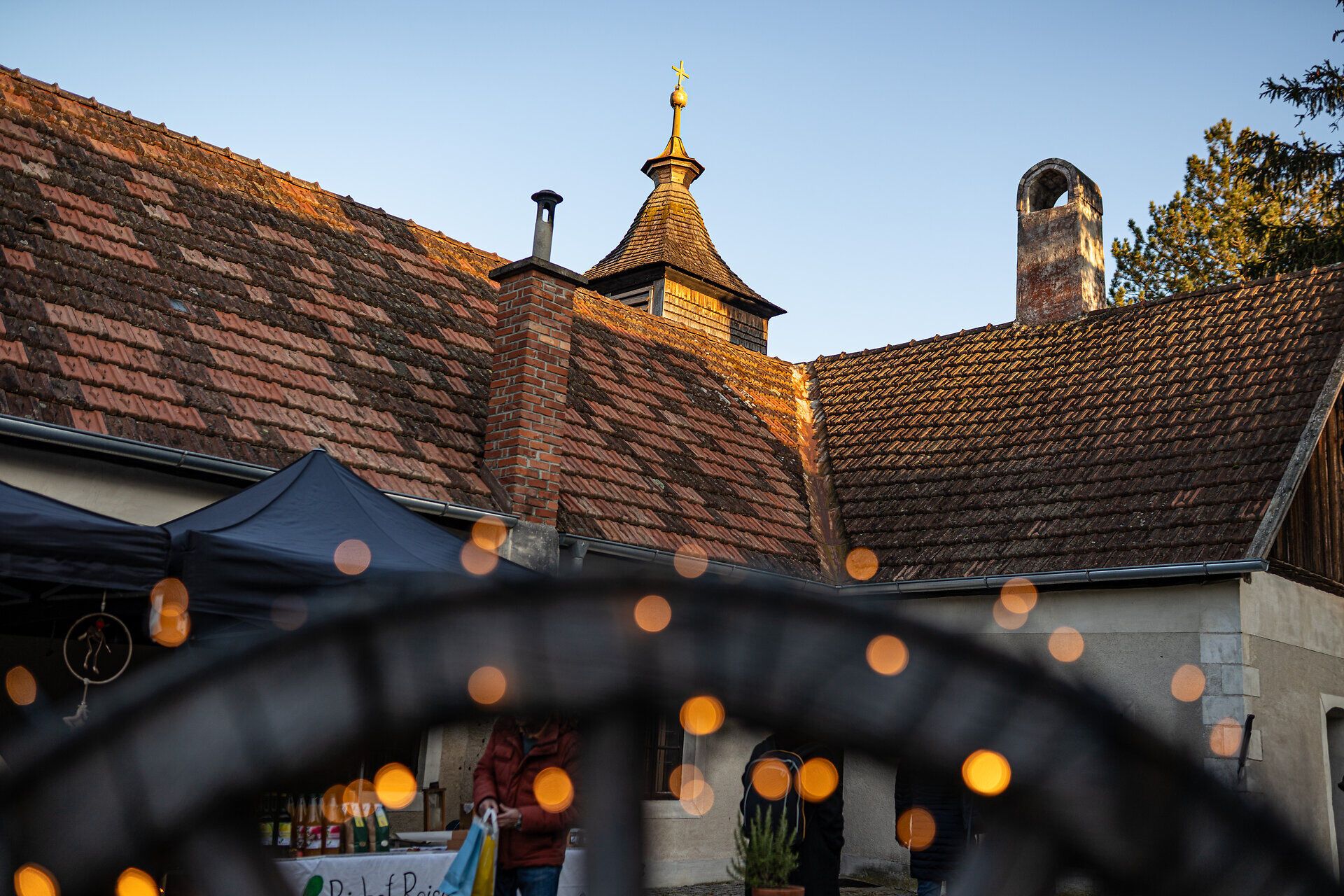 Historischer Innenhof mit Ziegeldächern und Lichterketten in Adventstimmung.