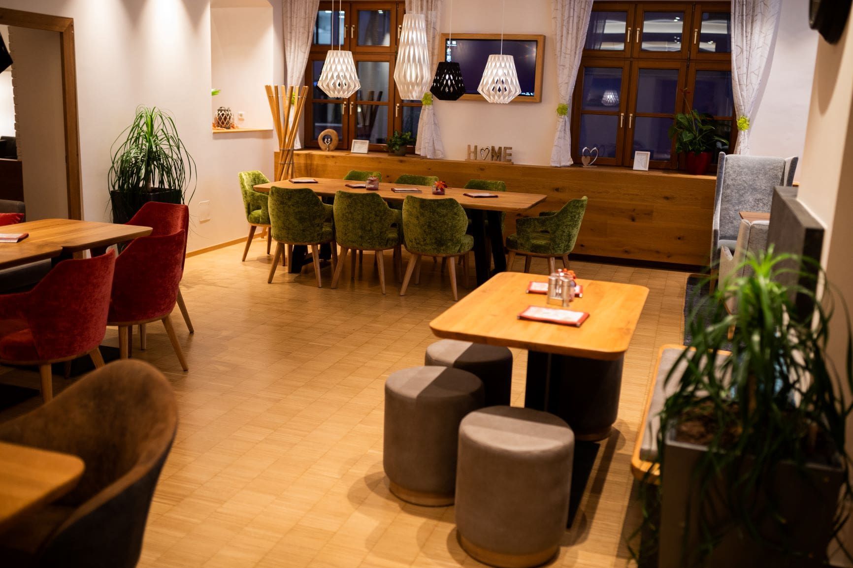 Innenansicht eines gemütlichen Bistros mit Holztischen, Stühlen und moderner Beleuchtung.