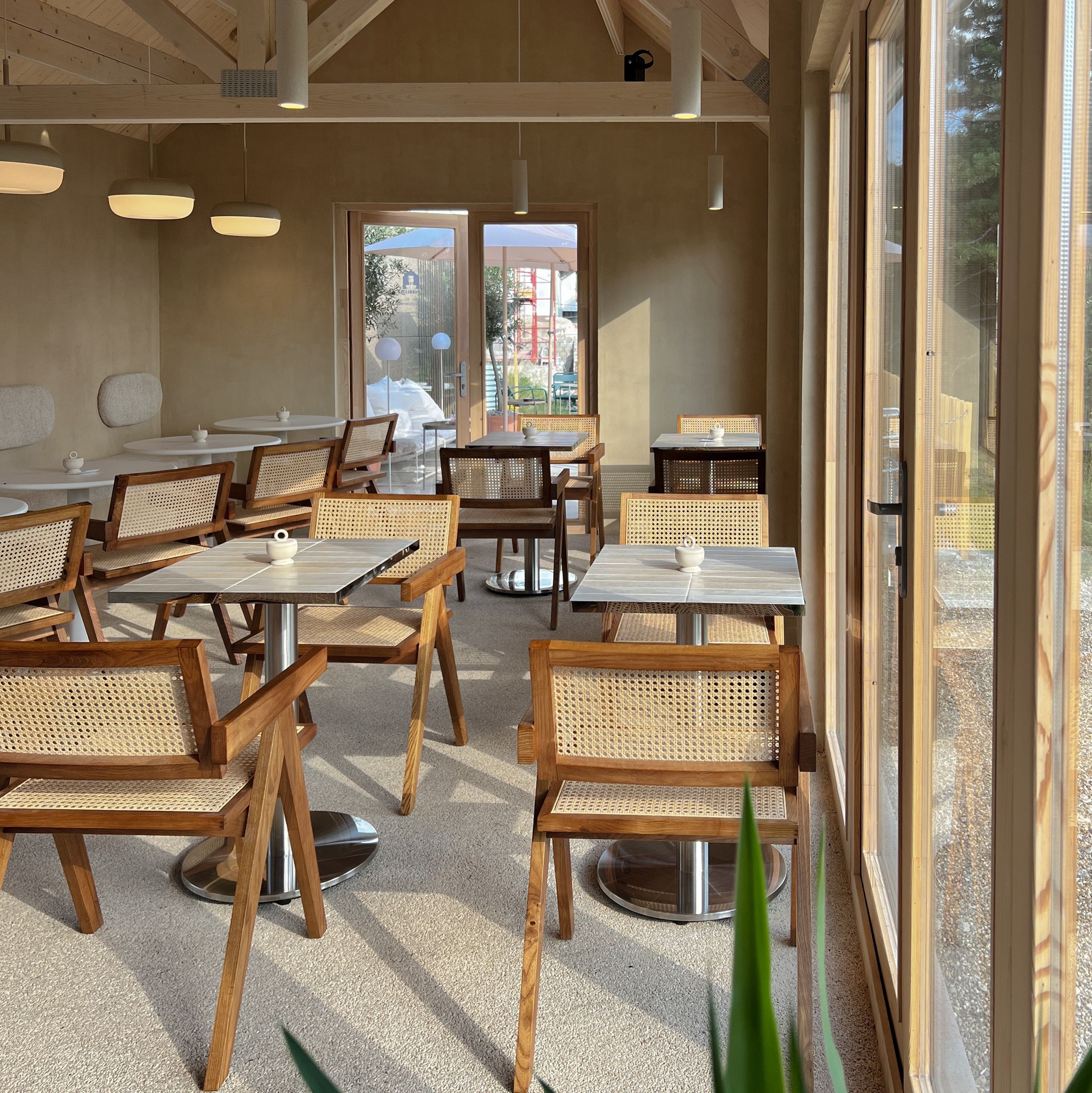 Innenbereich eines Cafés mit Holzmöbeln und großen Fenstern.