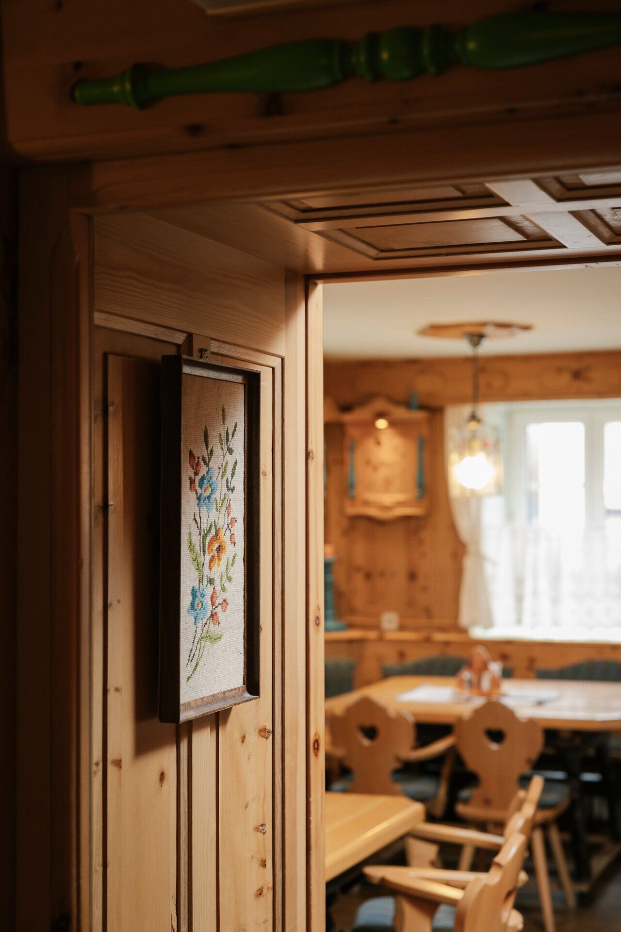 Gemütliche Stube mit Holzvertäfelungen, Tische und Stühle ebenfalls aus Holz mit blau bezogenen Sitzpolstern.