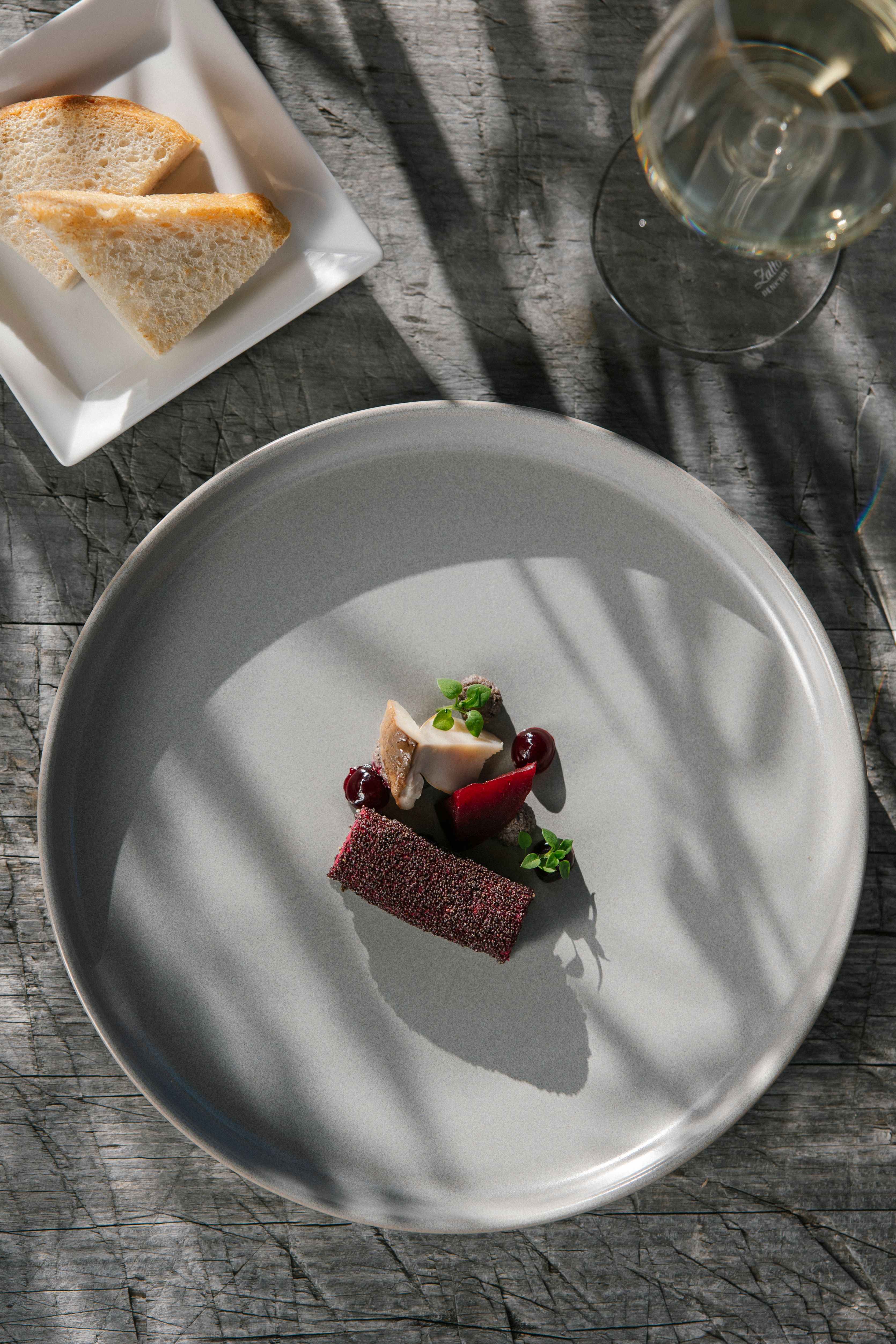 Ein weißes Teller mit einem ansprechend angerichteten Gourmetgericht mit Fleisch, Pilz und Soße.