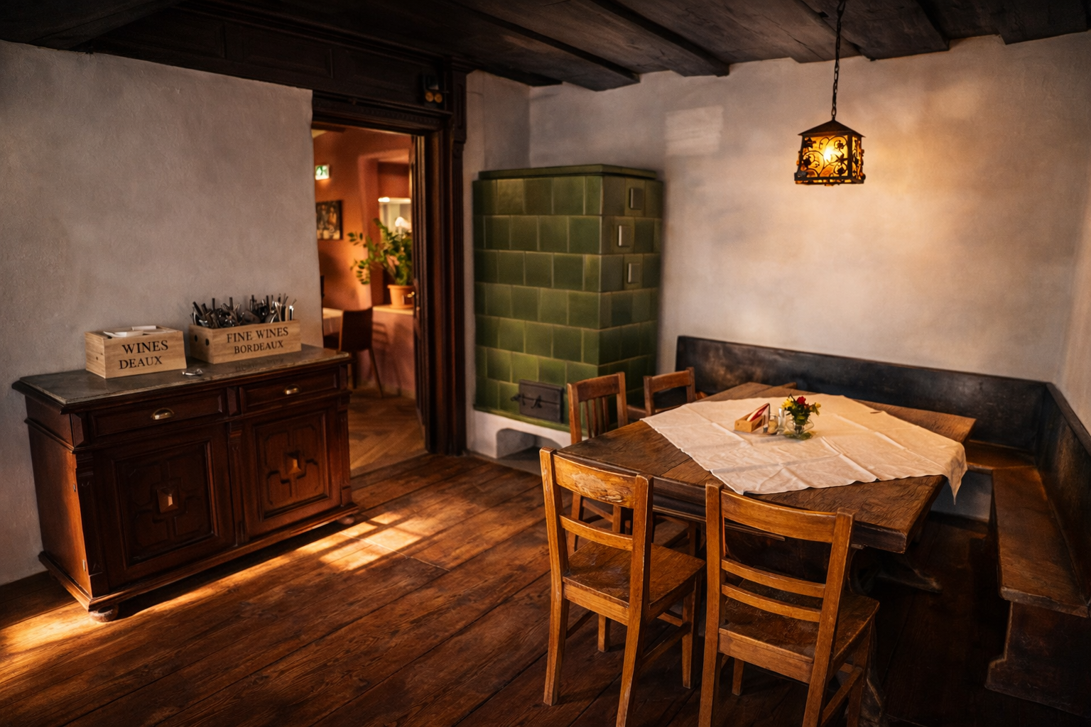 Gemütlicher Gastraum mit Holztisch, Stühlen, grünem Kachelofen und antikem Schrank.