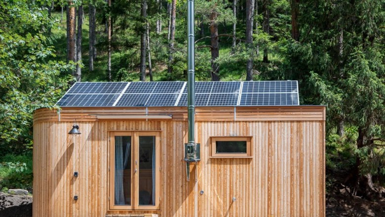 Ronja Außen, © WW Wohnwagon GmbH Kleines Holzhaus mit Solarpanelen auf dem Dach im Wald.