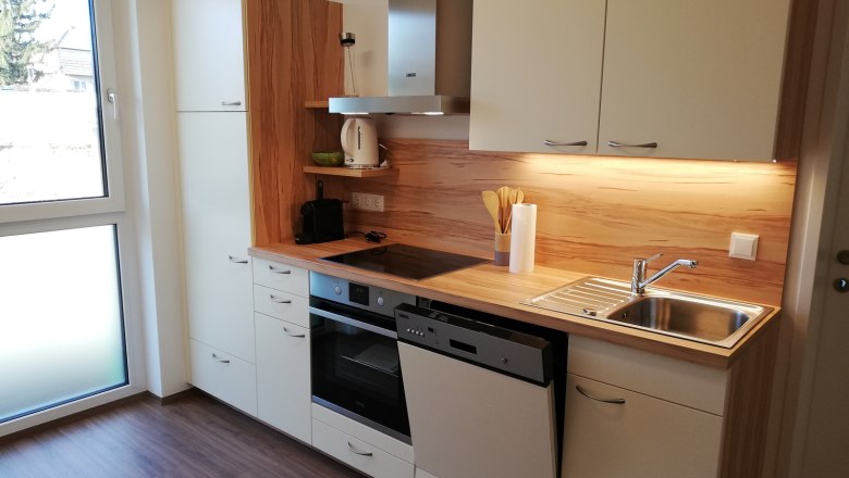 Modern kitchen with wooden worktop, sink, stove and dishwasher in a vacation bungalow.